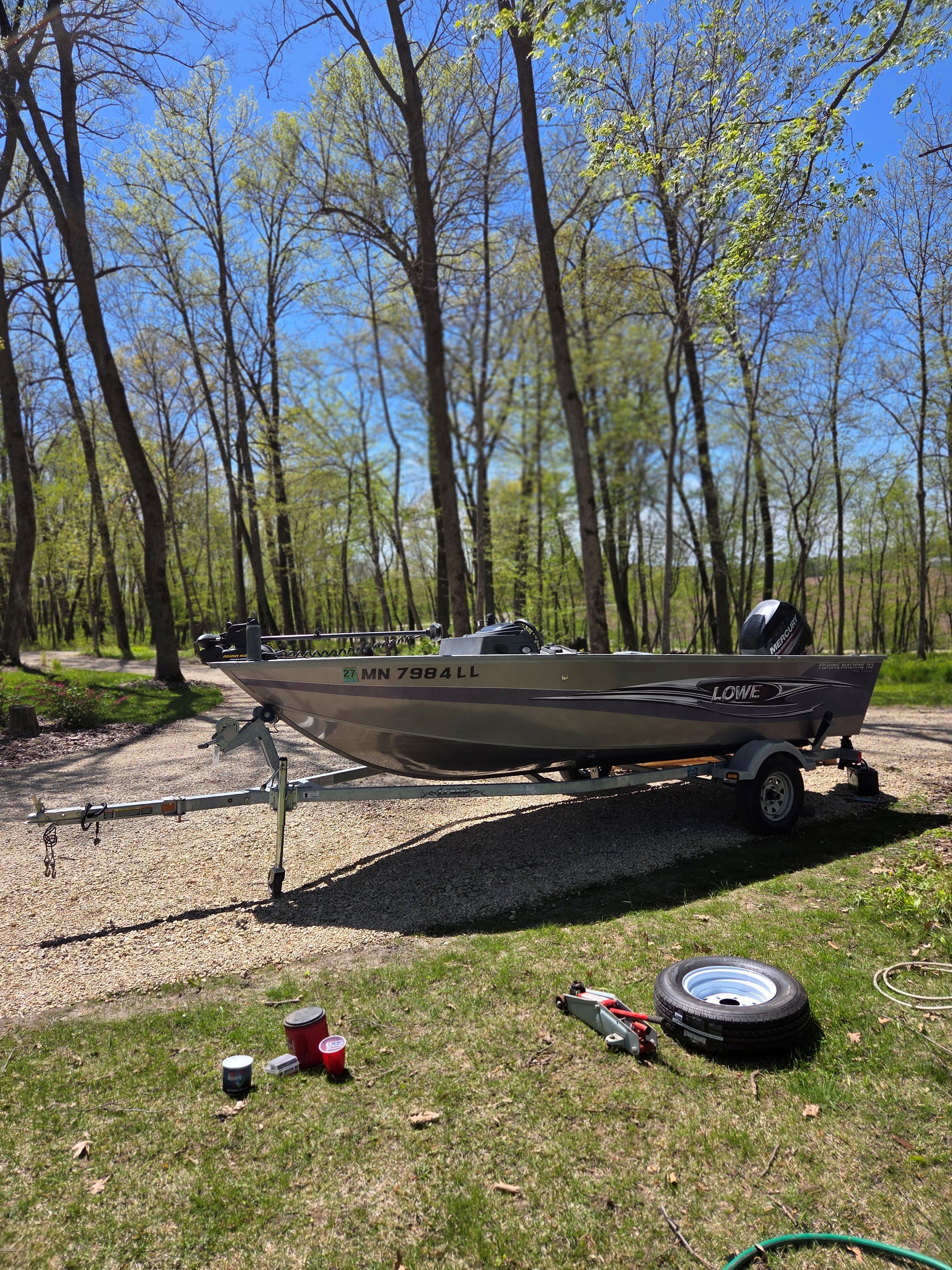 2015 Lowe Fishing Machine 165 Poly Camo boat parked in wooded area.