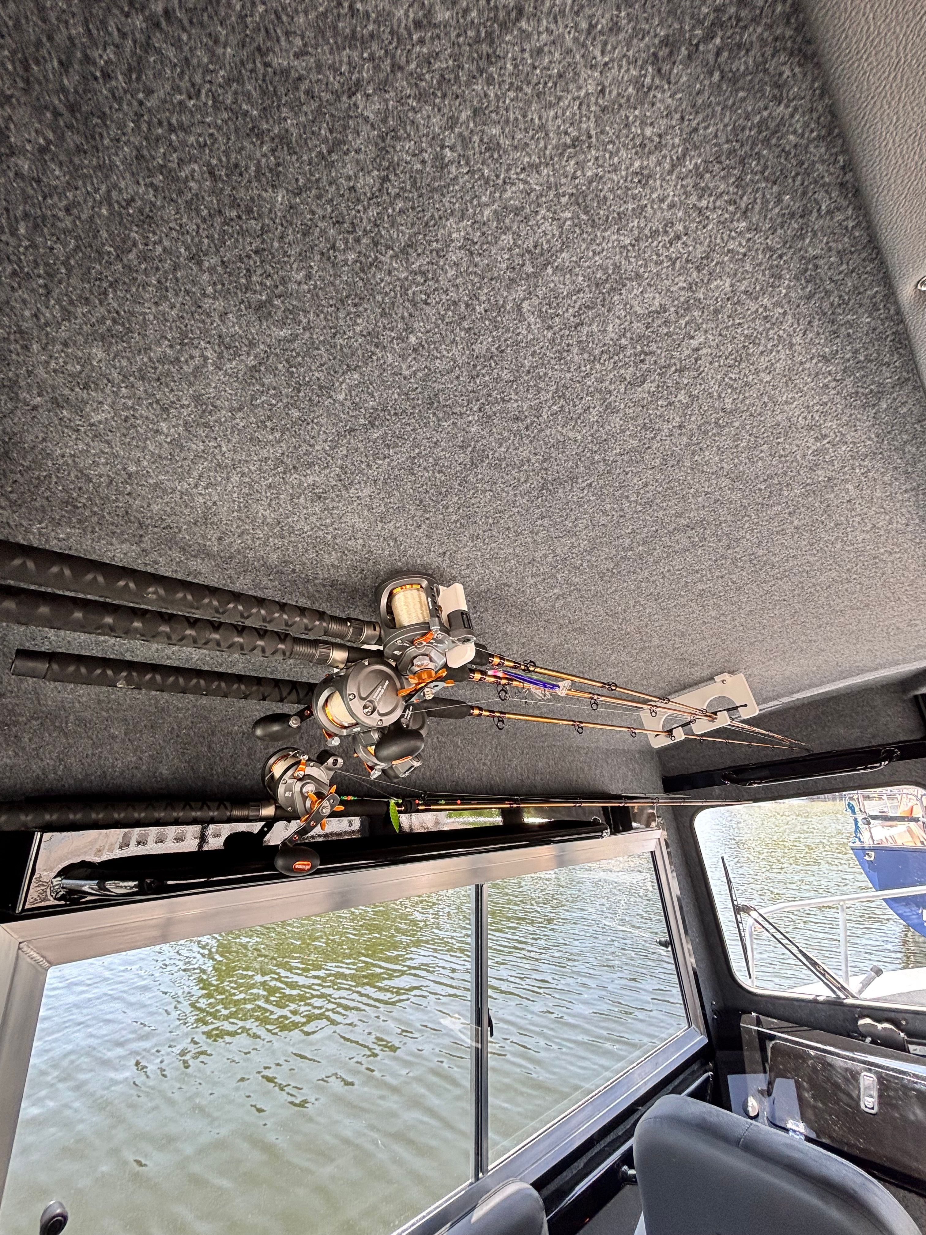 Fishing rods are mounted on the ceiling of a boat, overlooking the water.