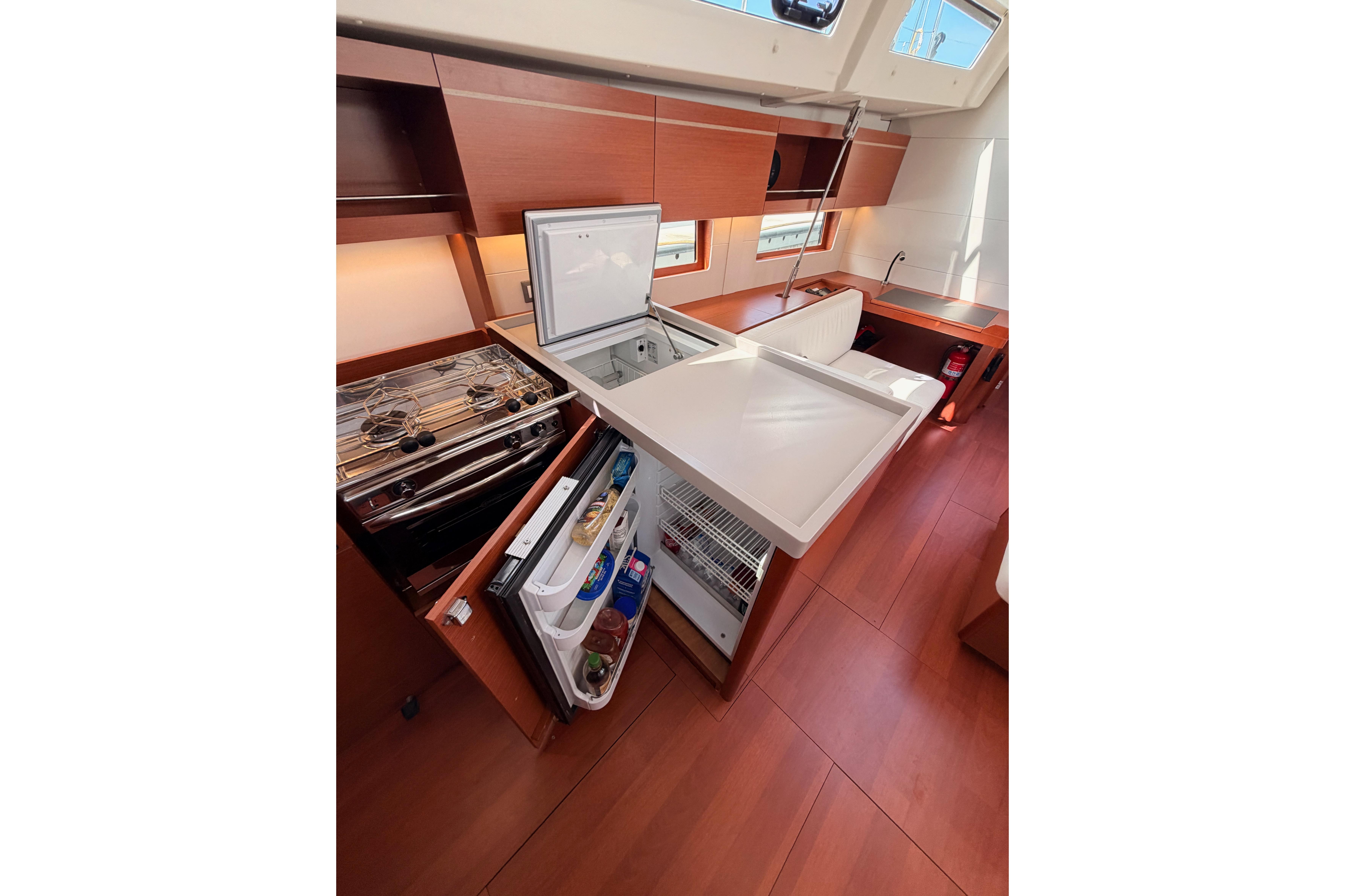 Interior of 2020 Beneteau Oceanis 46.1 yacht kitchen with open fridge and stove.