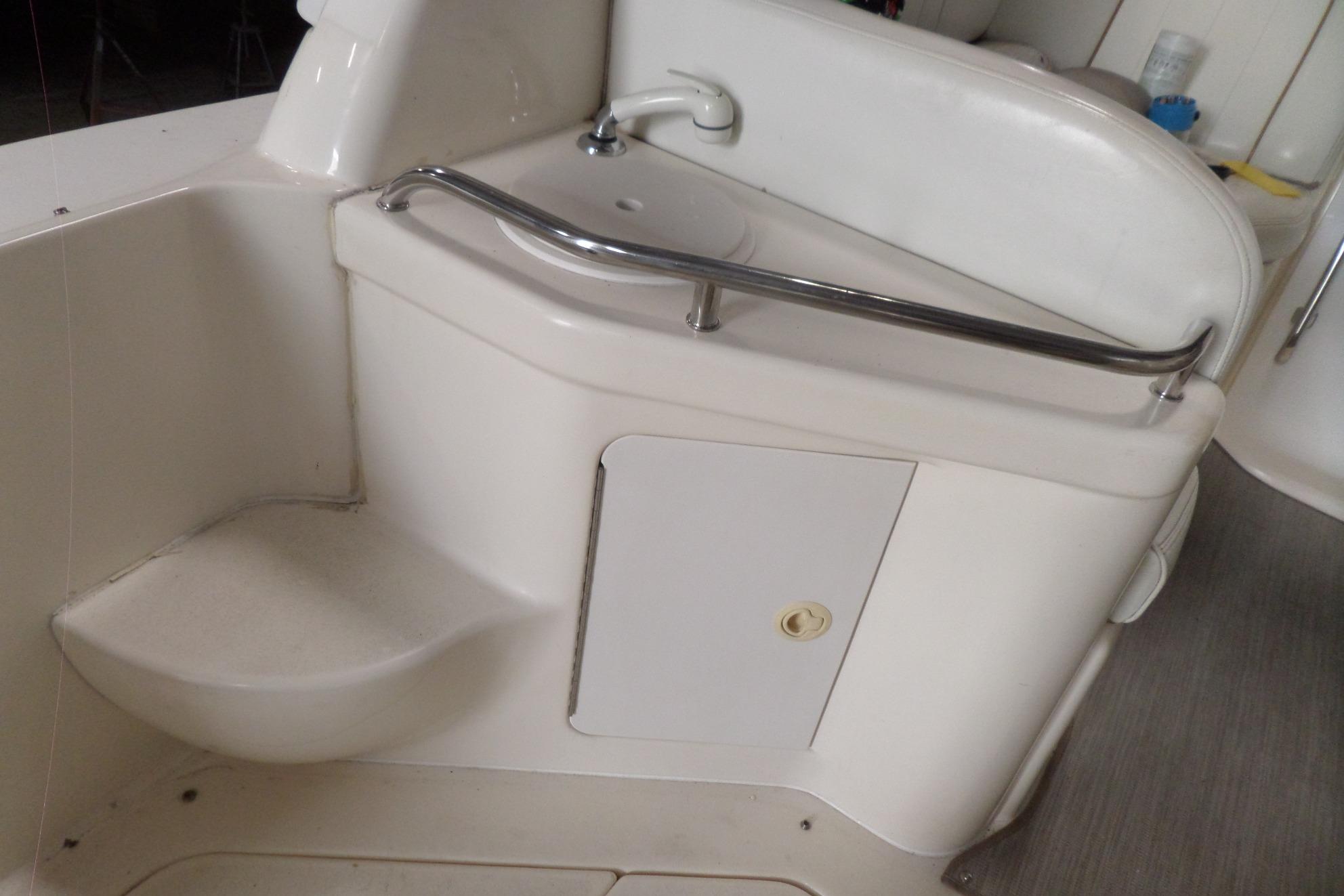 1997 Sea Ray 290 Sundancer boat interior with sink and storage compartment.
