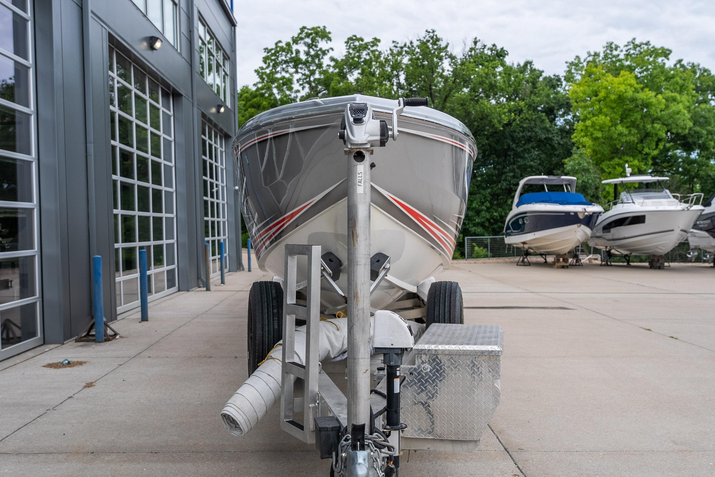 2006 Cigarette 39' Top Gun Unlimited boat on trailer near modern building.