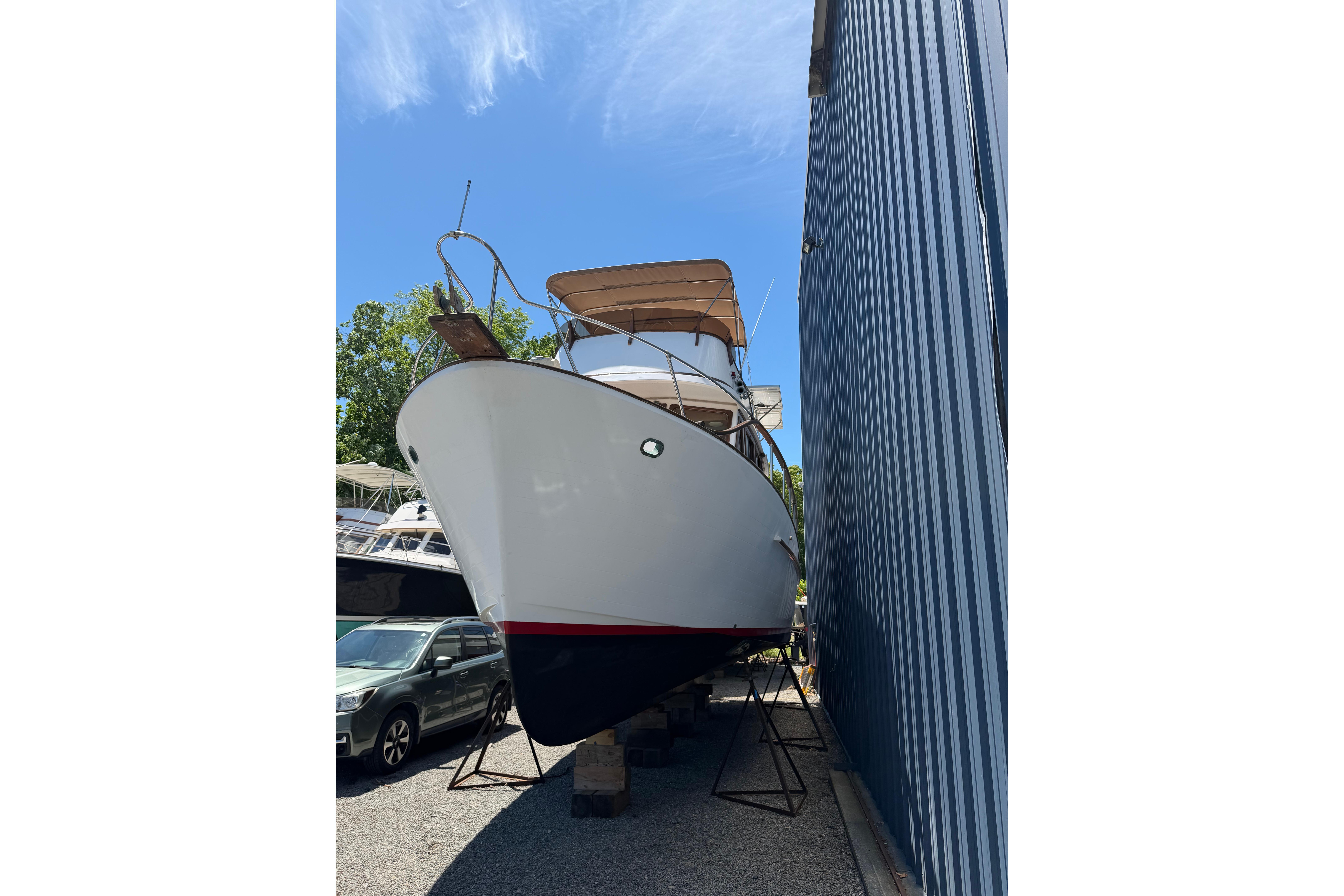 1987 Marine Trader 36 boat on stands beside a blue building under a clear sky.