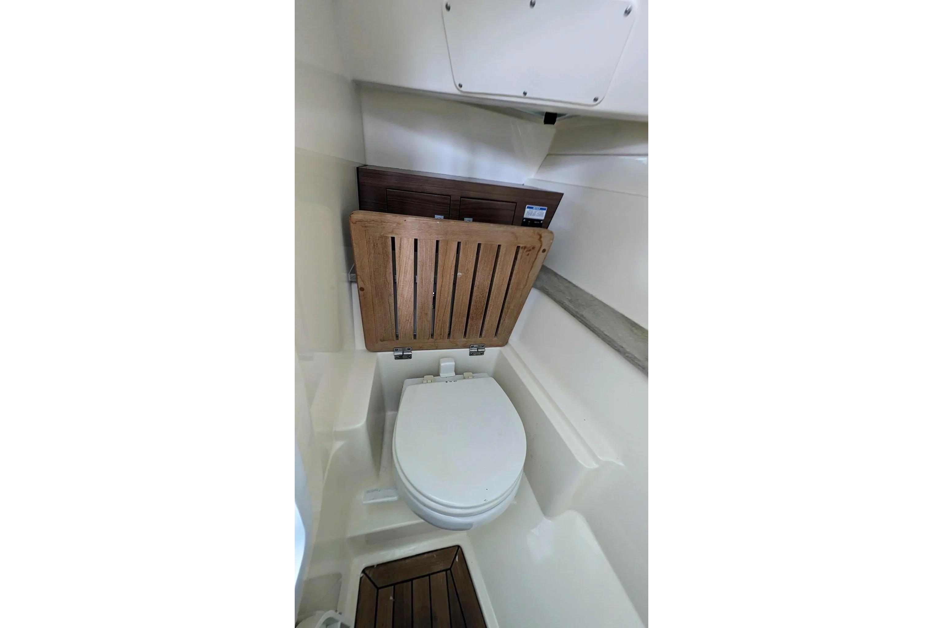 2017 Boston Whaler 320 Vantage boat interior with compact marine toilet and wooden seat.