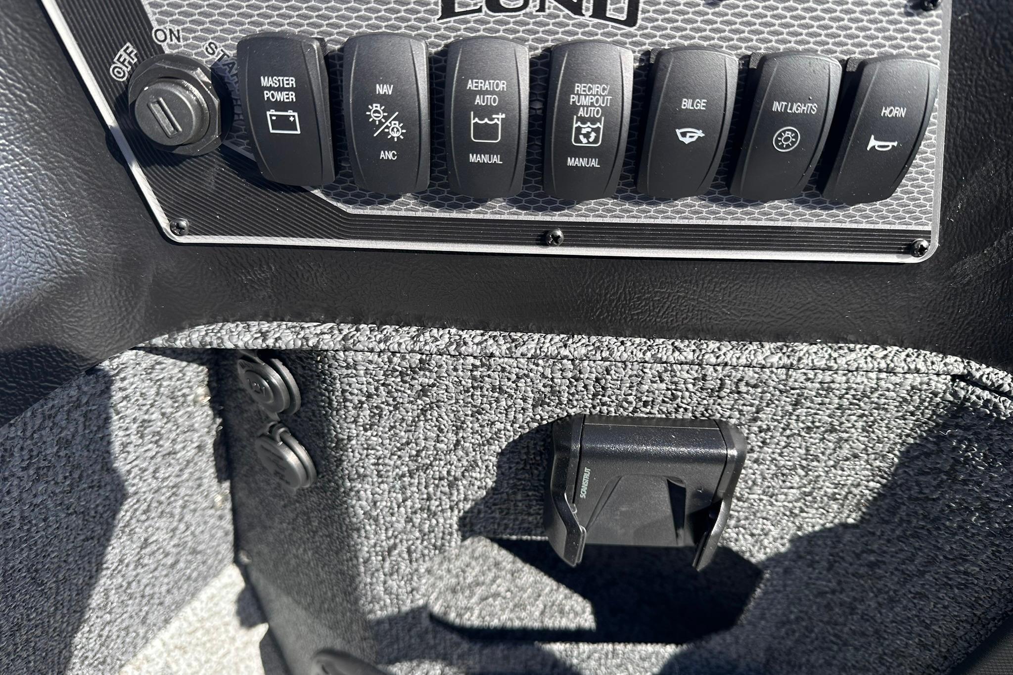 Control panel of 2026 Lund 1875 Impact XS SS boat with various switches.
