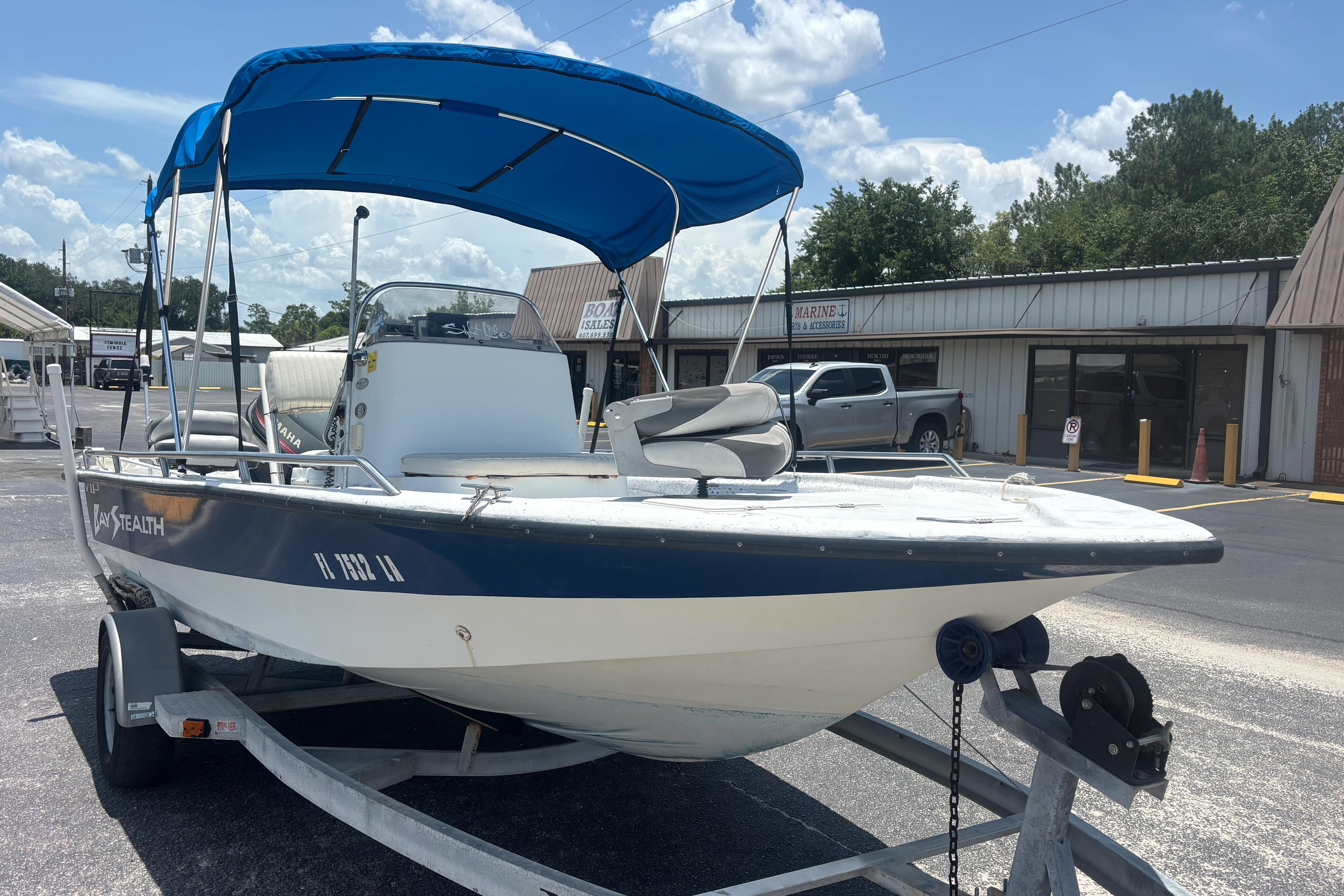 2000 VIP 1880 BAY STEALTH boat with blue canopy on trailer, parked outdoors.