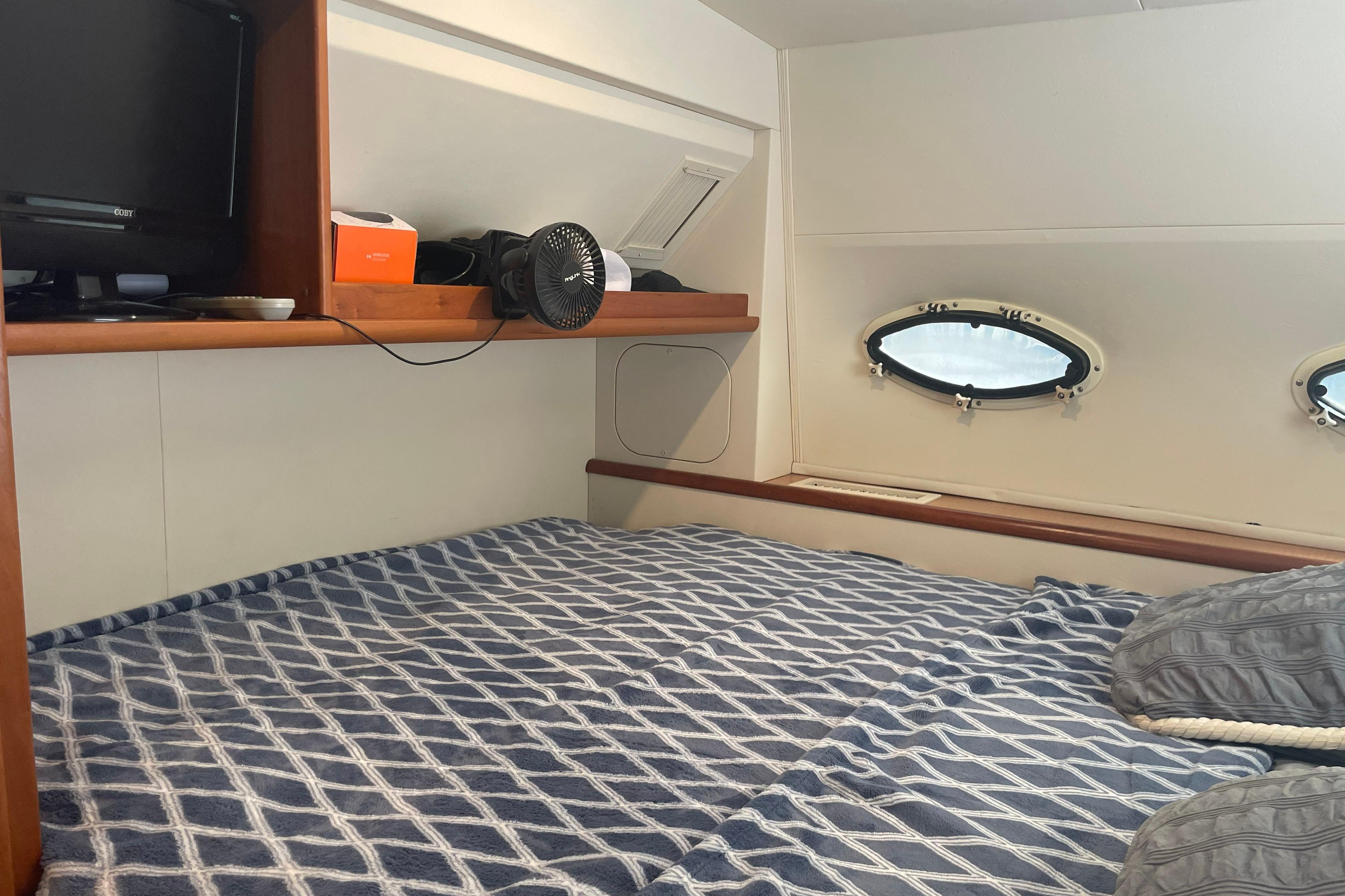 1999 Silverton 322 Motor Yacht cabin with bed, portholes, and shelf storage.