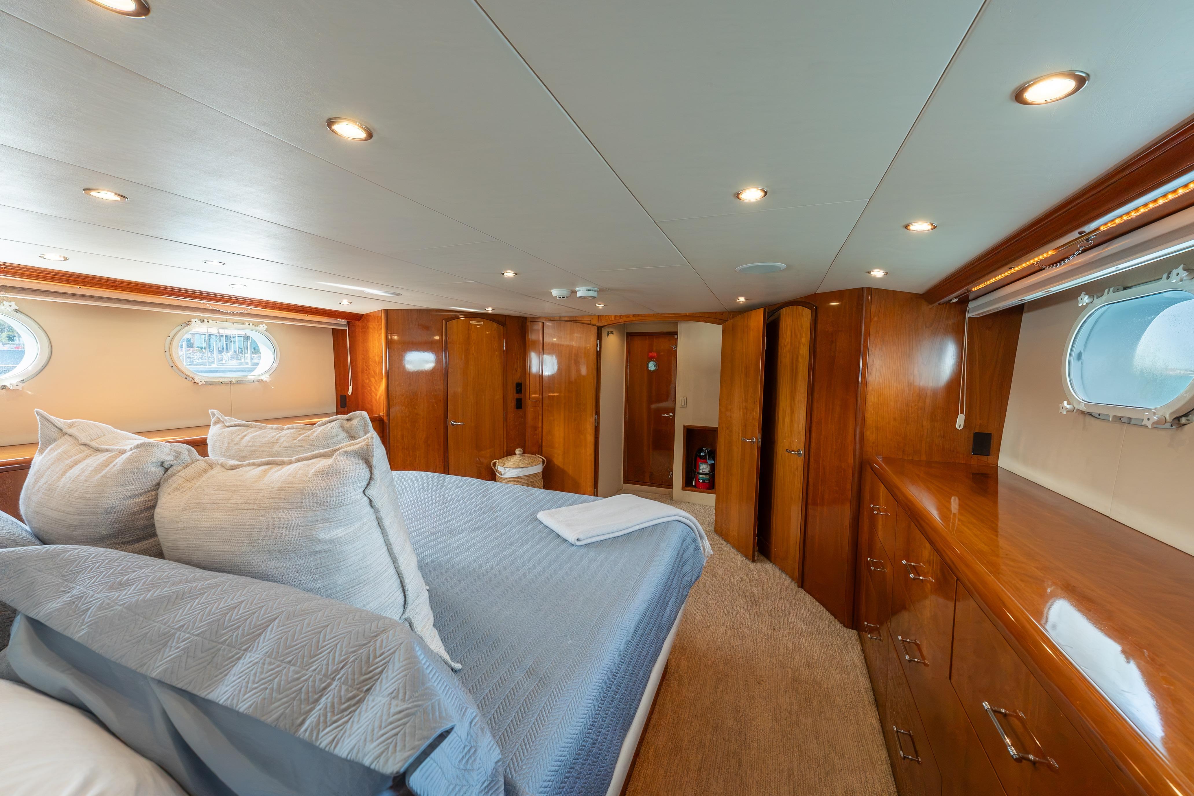 Luxurious bedroom interior of 2004 Hatteras 75 Sport Deck Motor Yacht with wood finishes.