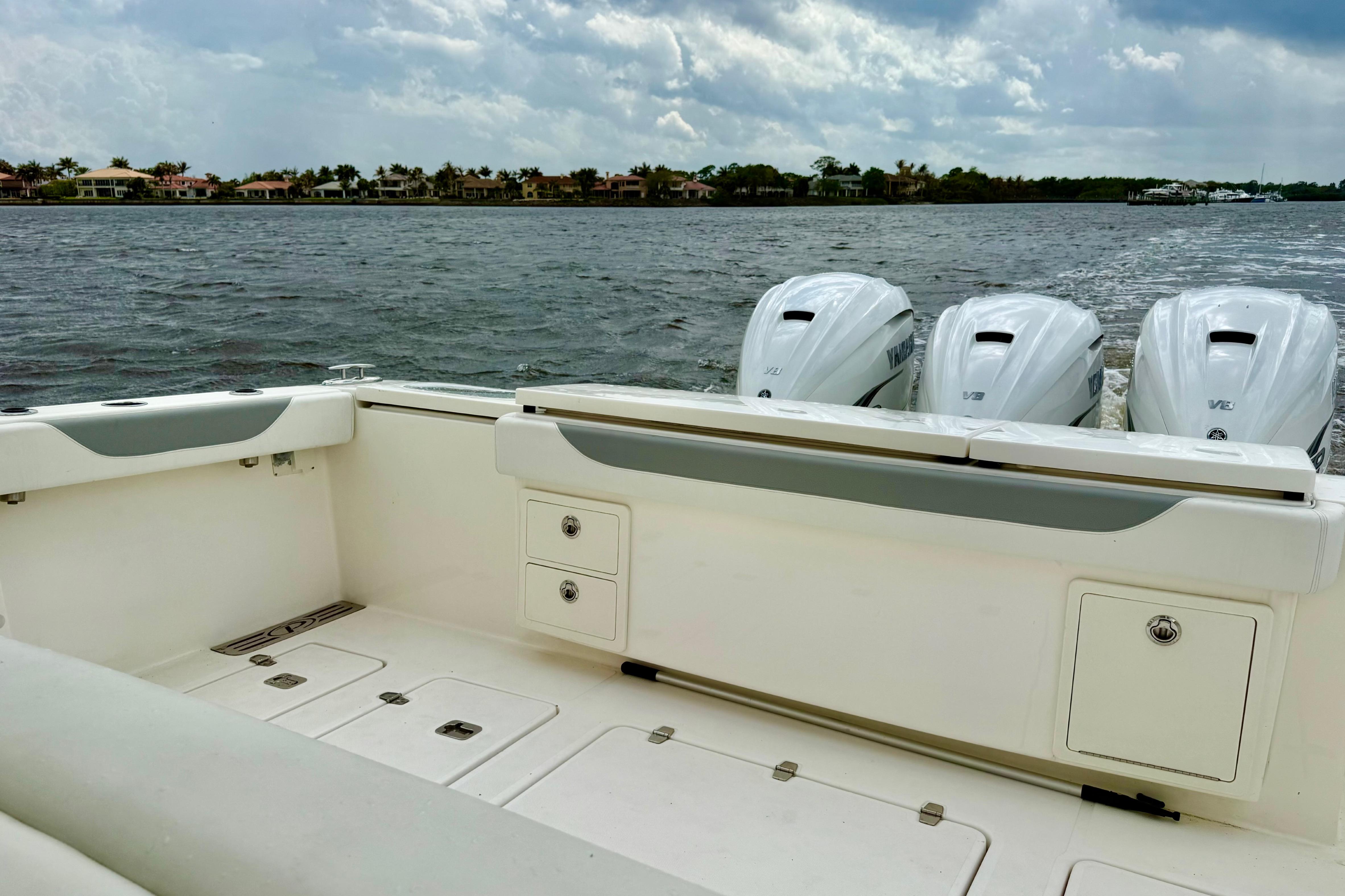 2020 Pursuit S 408 Sport boat with triple Yamaha engines on a calm waterway.