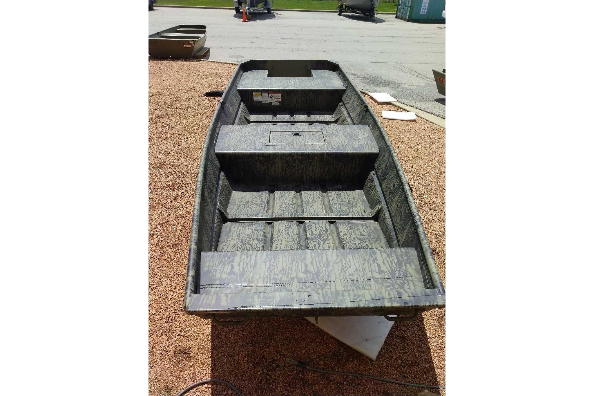 2026 Tracker Grizzly 15 Jon boat with camouflage design on gravel surface.