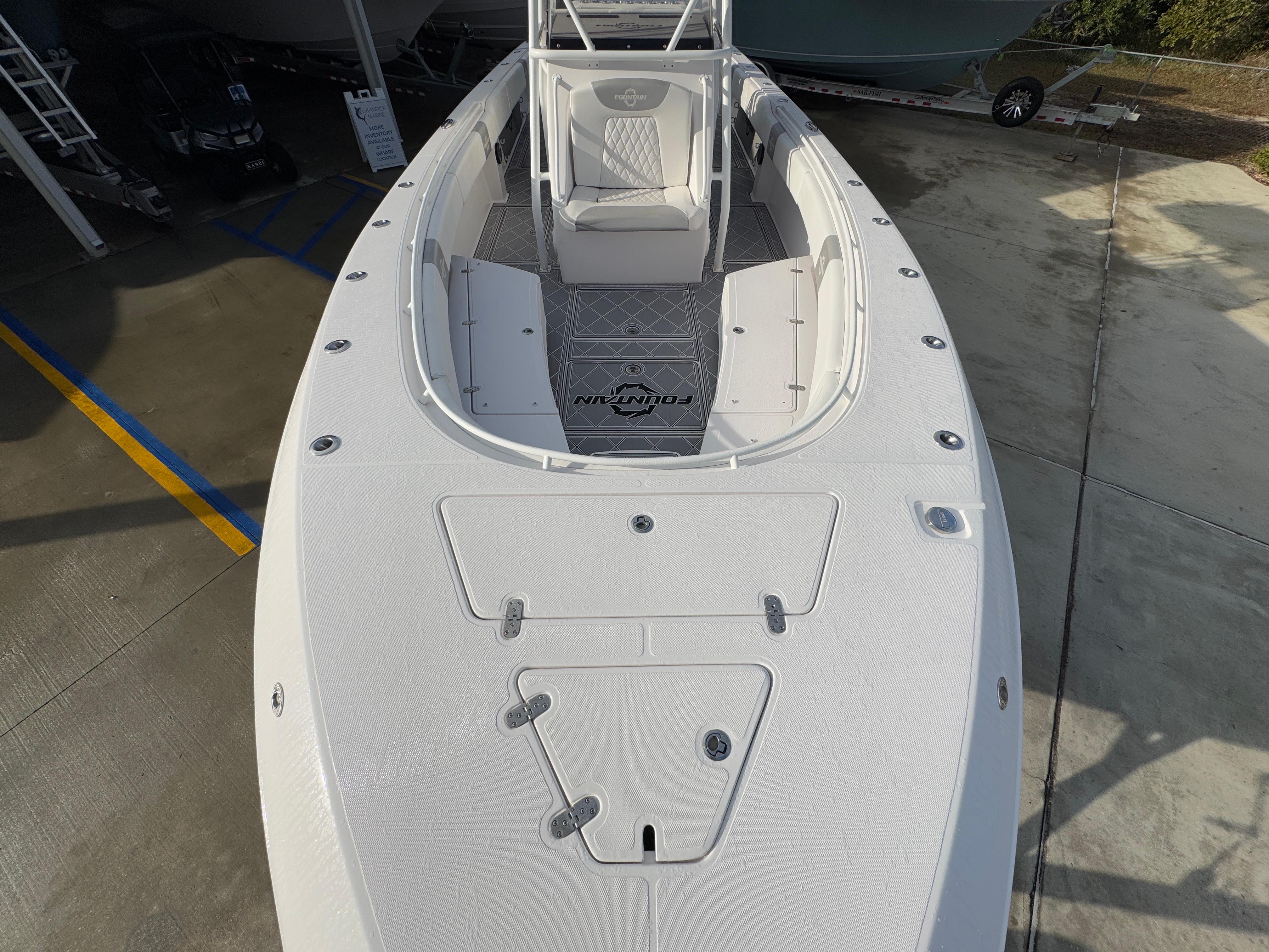 2018 Fountain 34 CC boat, top view, white deck, parked on concrete.