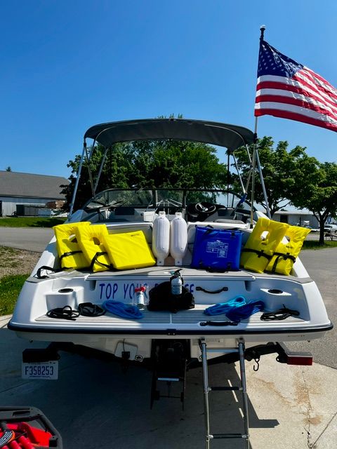 2023 Yamaha SX190 boat with yellow life jackets and American flag, parked on a trailer.