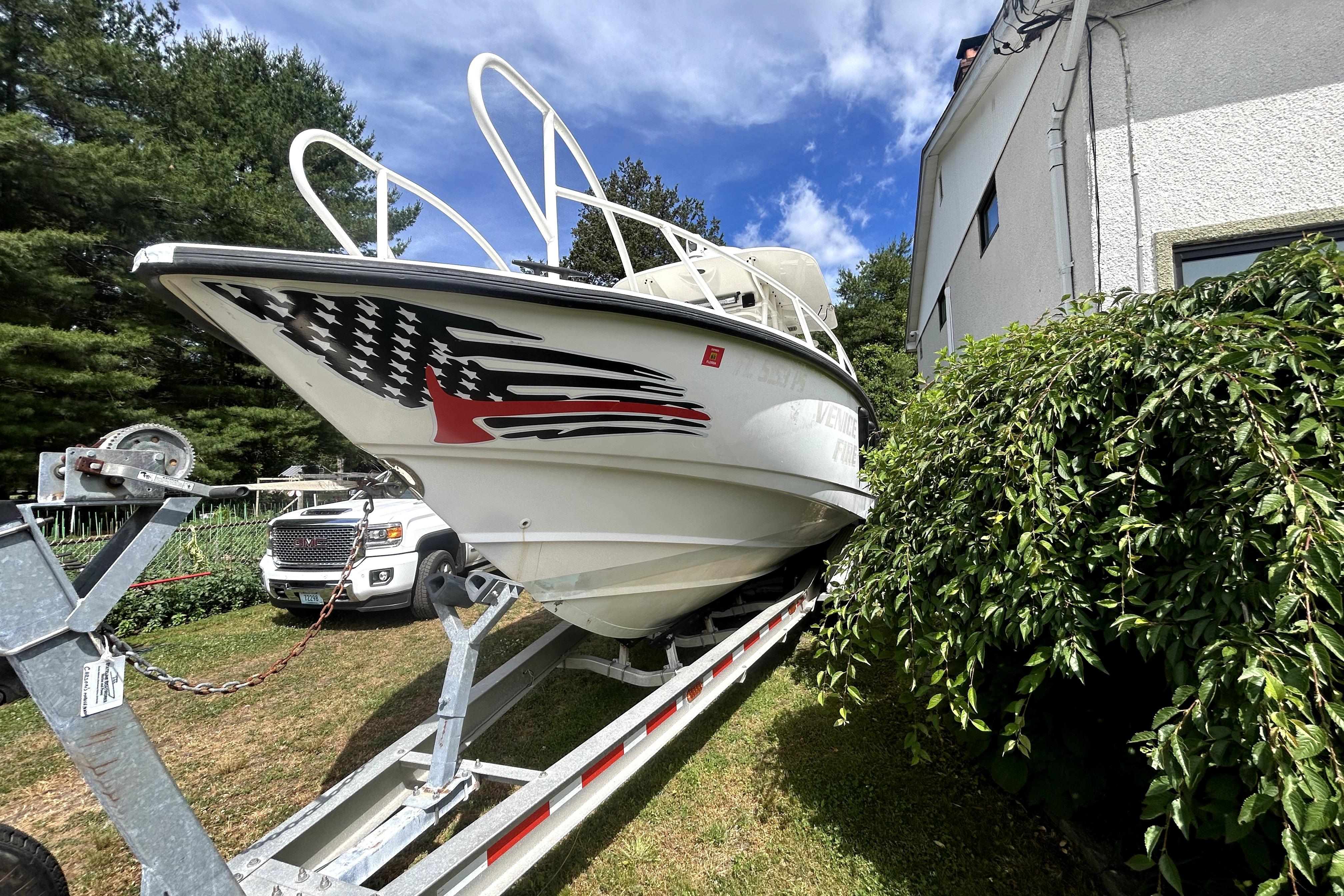 2012 Boston Whaler 320 Outrage boat on trailer, parked beside a house.