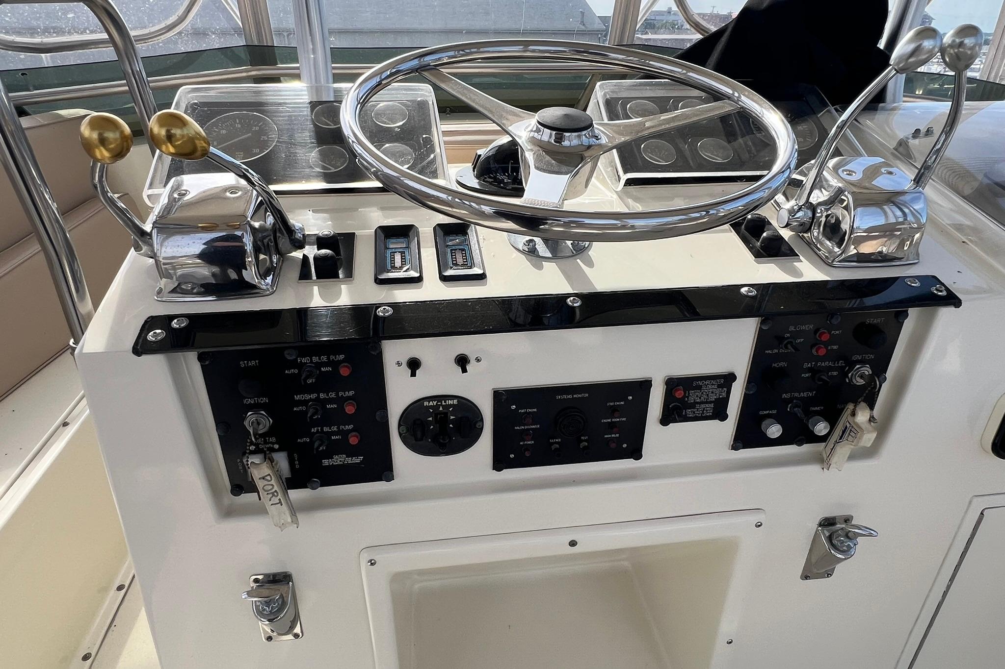 Control panel of a 1990 Hatteras 41 Convertible boat with steering wheel and throttle levers.