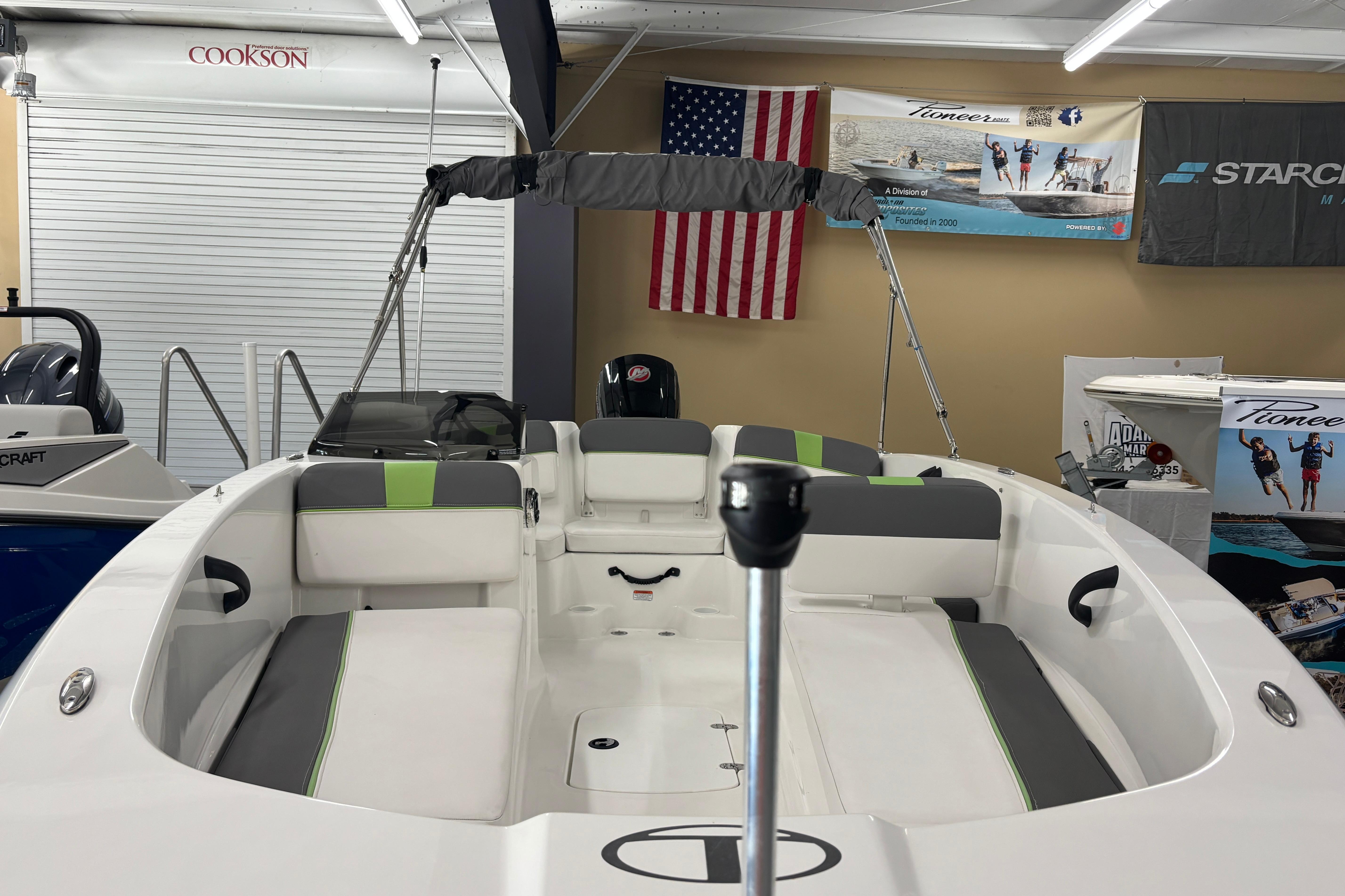 2024 Tahoe T18 boat interior with seating, showroom display, and American flag backdrop.