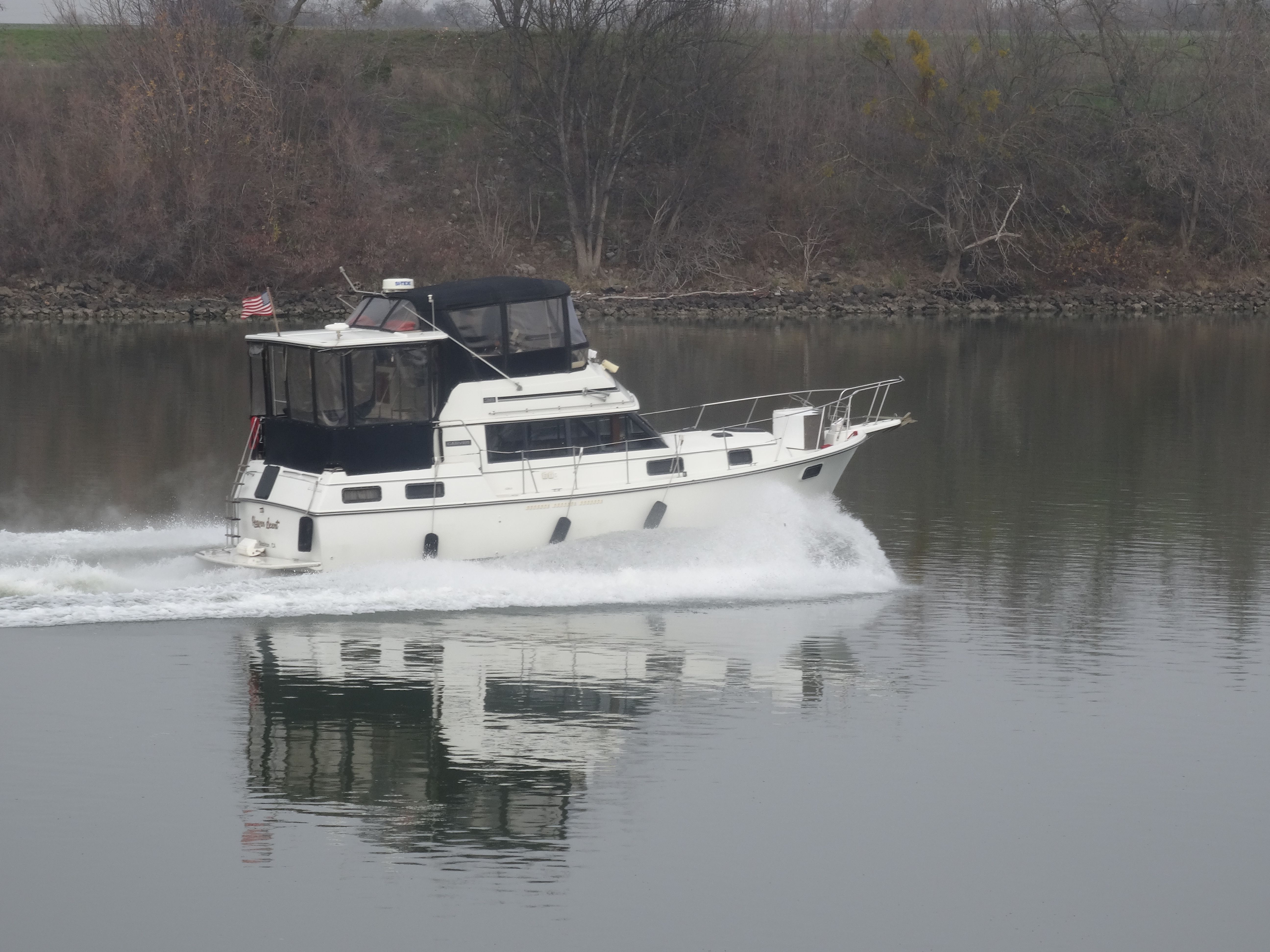 A 1988 Carver 3607 Aft Cabin Motor Yacht cruising on a calm river.