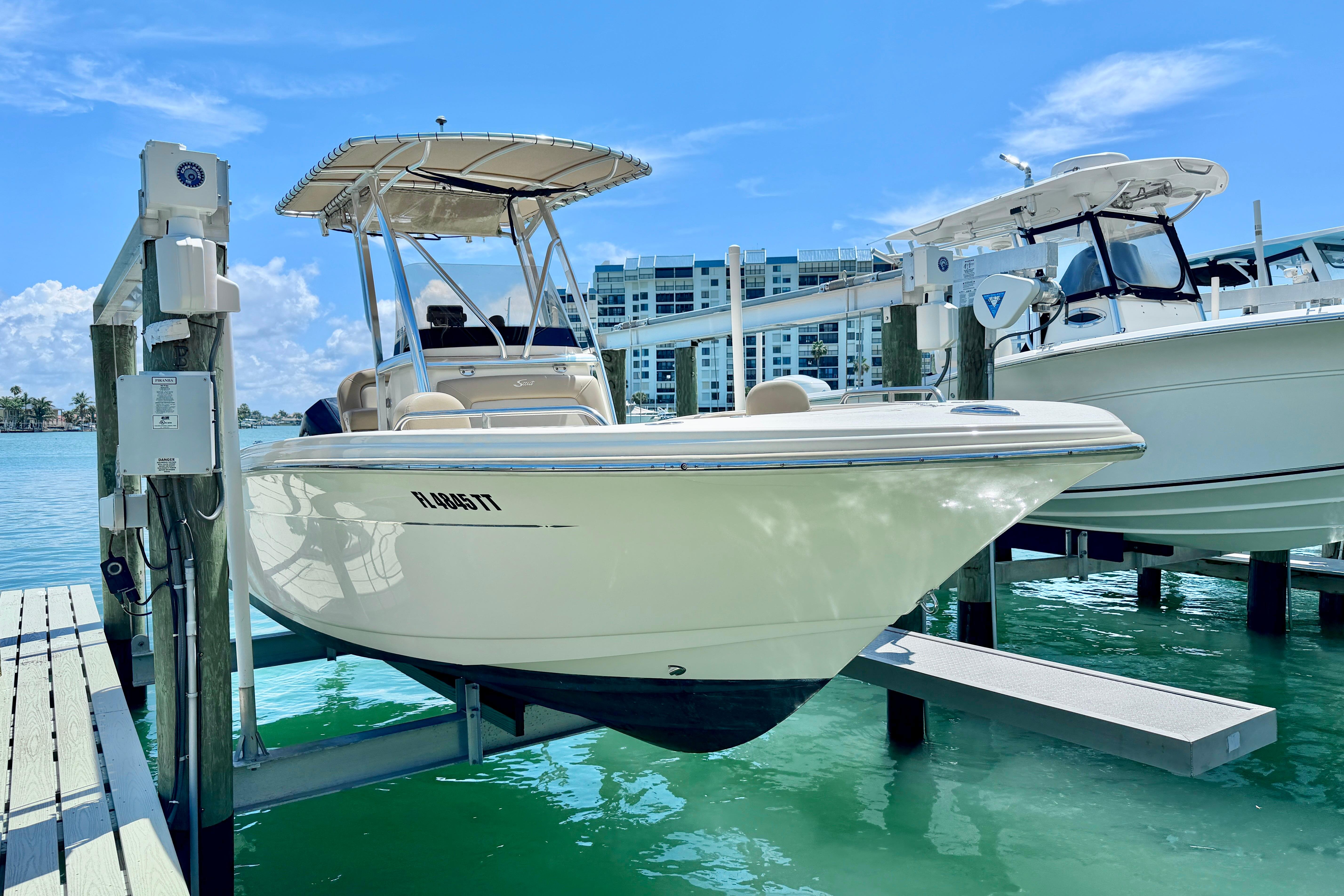 2022 Scout 215 XSF boat docked on a lift, with clear blue water and sky.