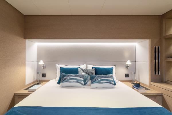Luxurious bedroom interior of 2025 Lagoon SIXTY 5 yacht with modern design and ambient lighting.