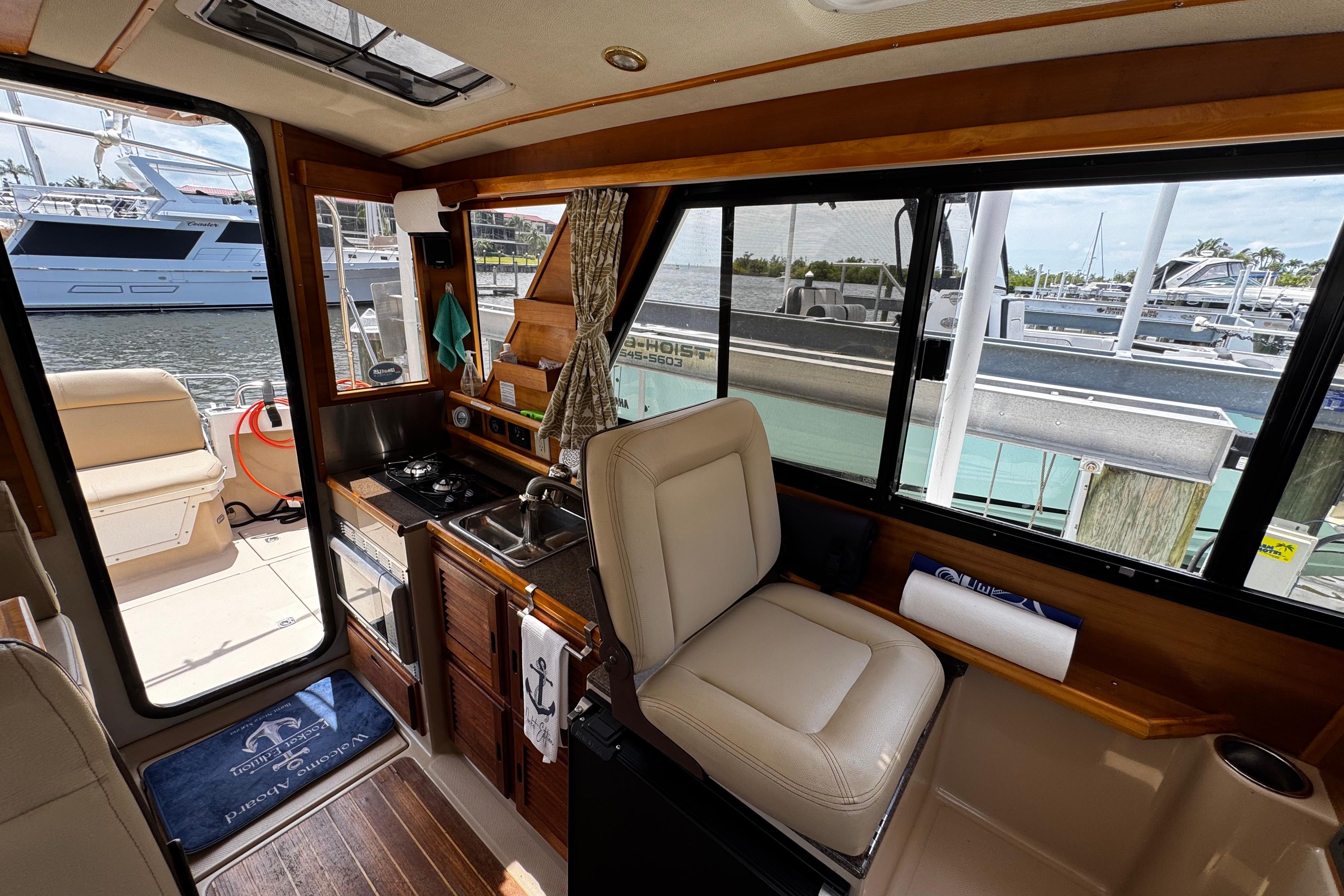 Interior of 2012 Cutwater C-26 boat with kitchenette and seating, docked at marina.