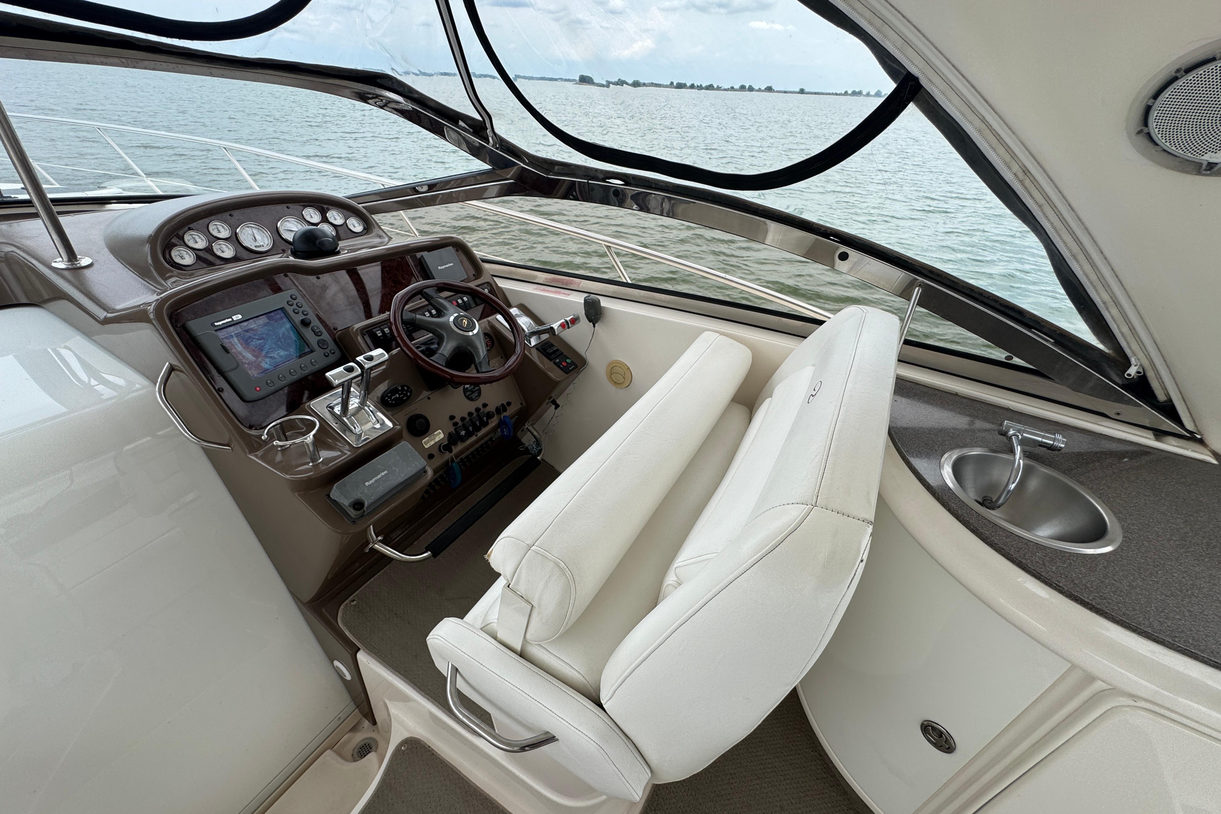 2005 Regal Commodore 4260 yacht cockpit with steering wheel, navigation system, and ocean view.