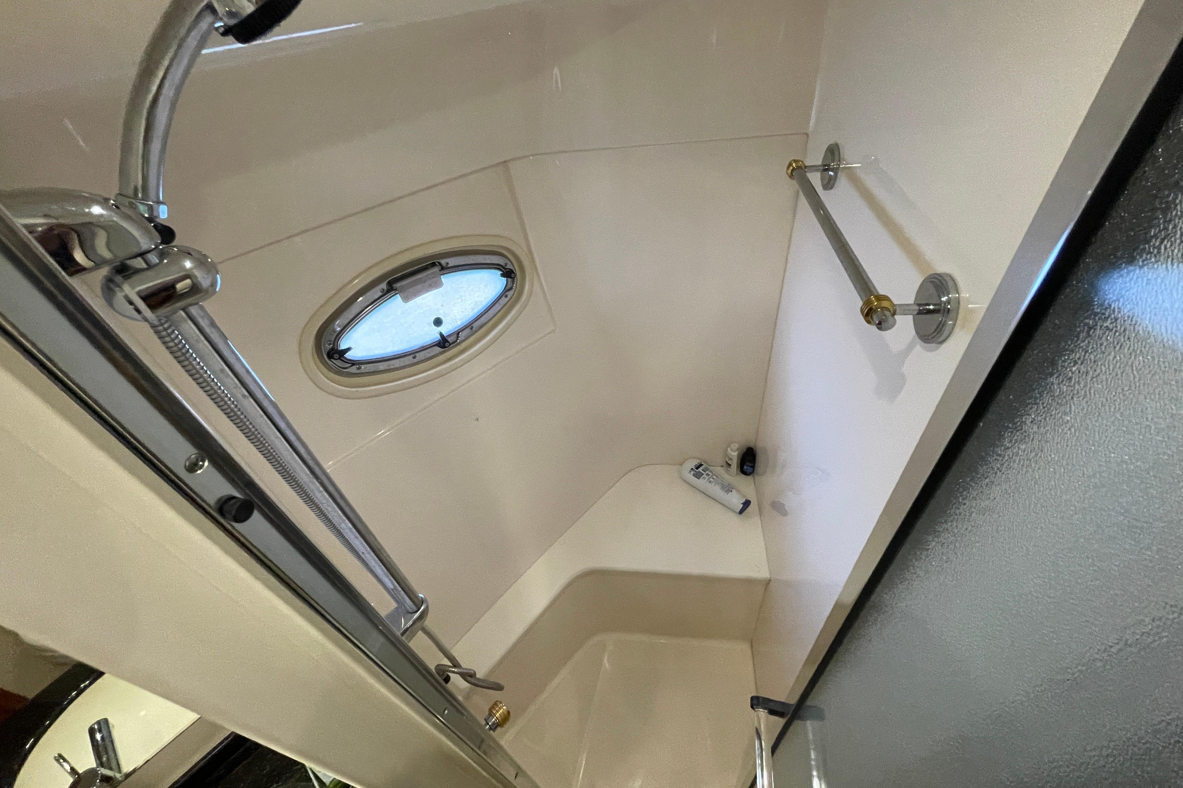 Shower area in 2002 Carver 570 Voyager Pilothouse with porthole and chrome fixtures.