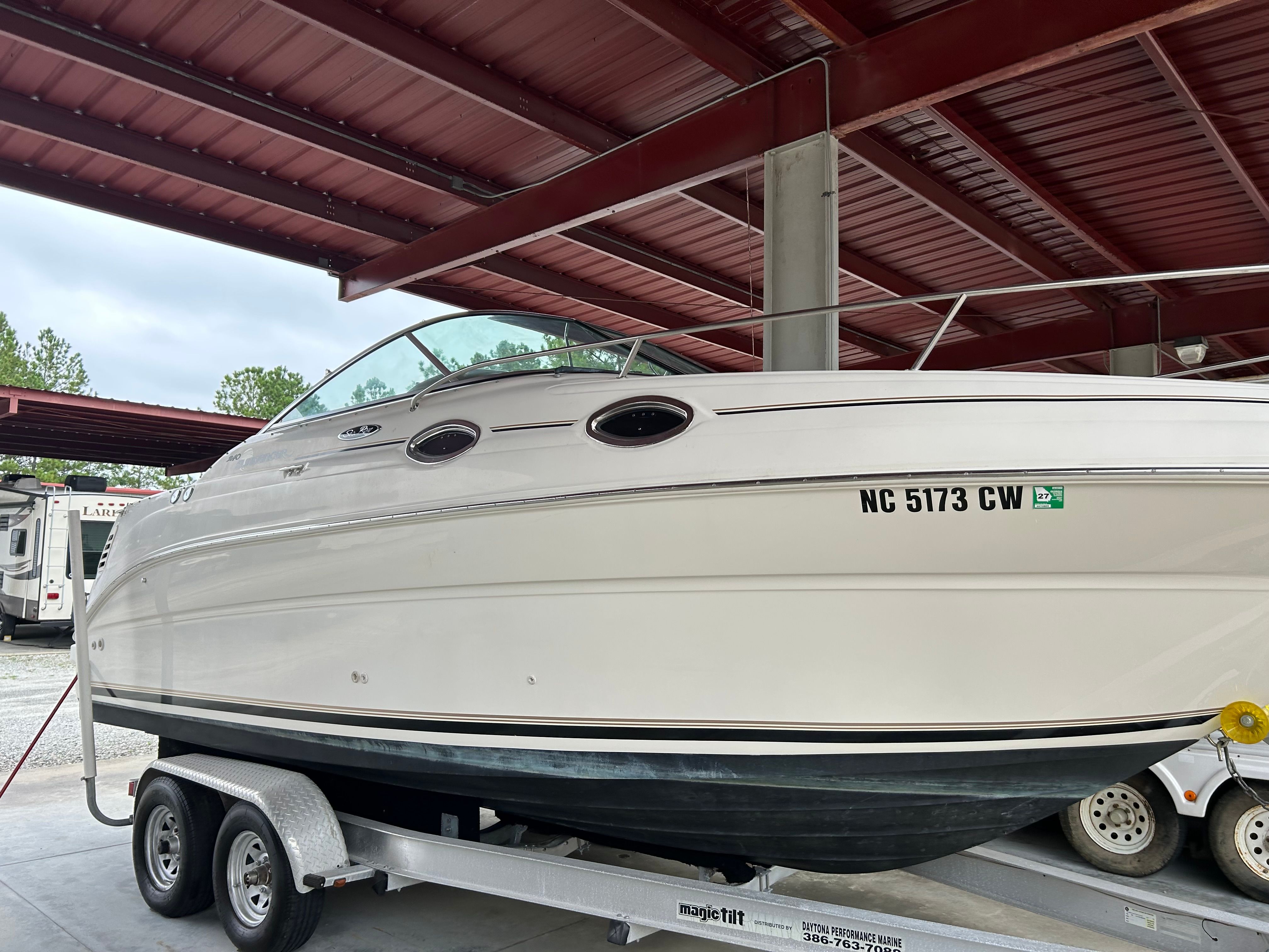 2003 Sea Ray 240 Sundancer boat on trailer under metal roof.