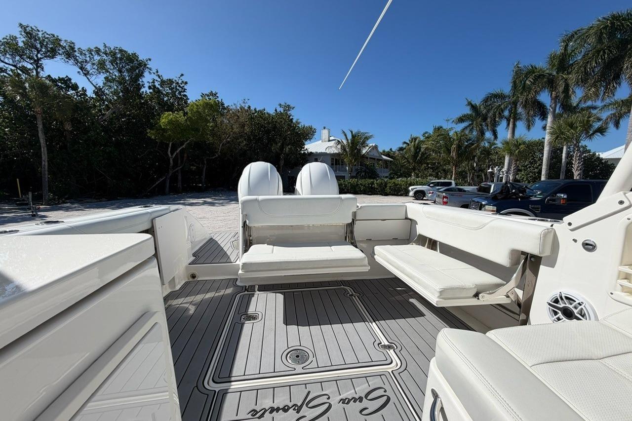 2021 Pursuit DC 266 Dual Console boat interior with seating, parked near palm trees.