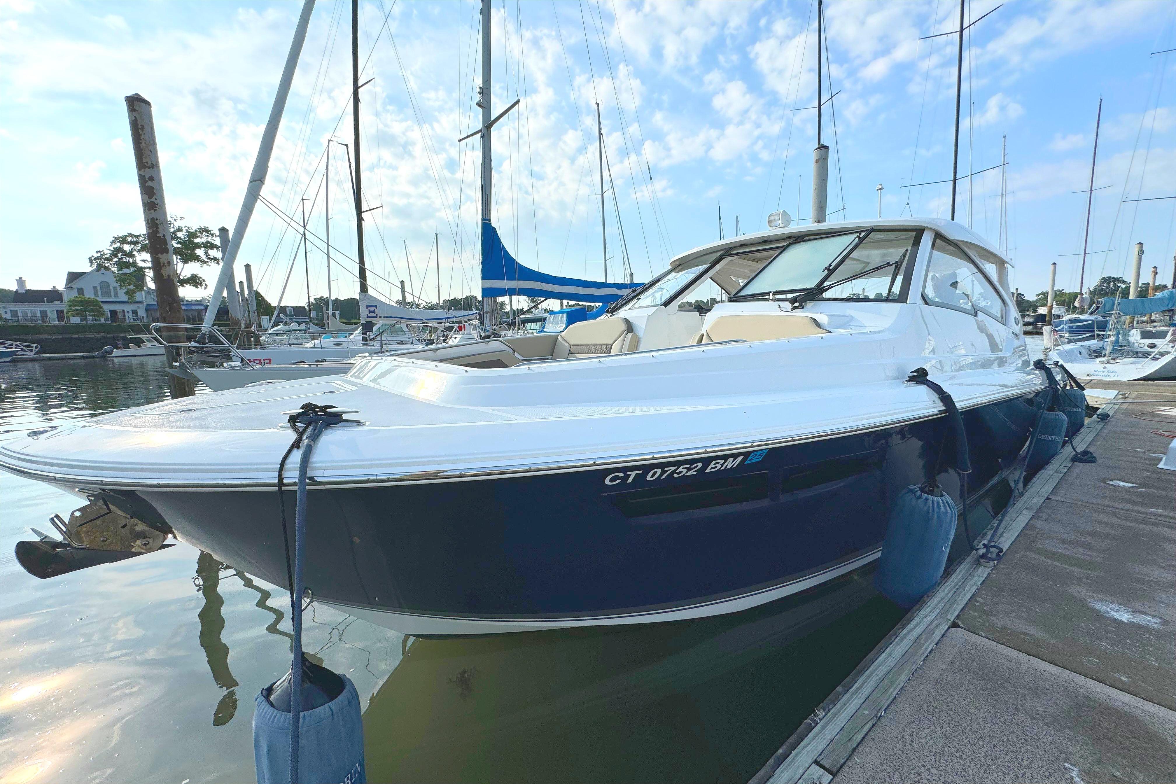 2021 Pursuit DC 365 boat docked at a marina with sailboats in the background.