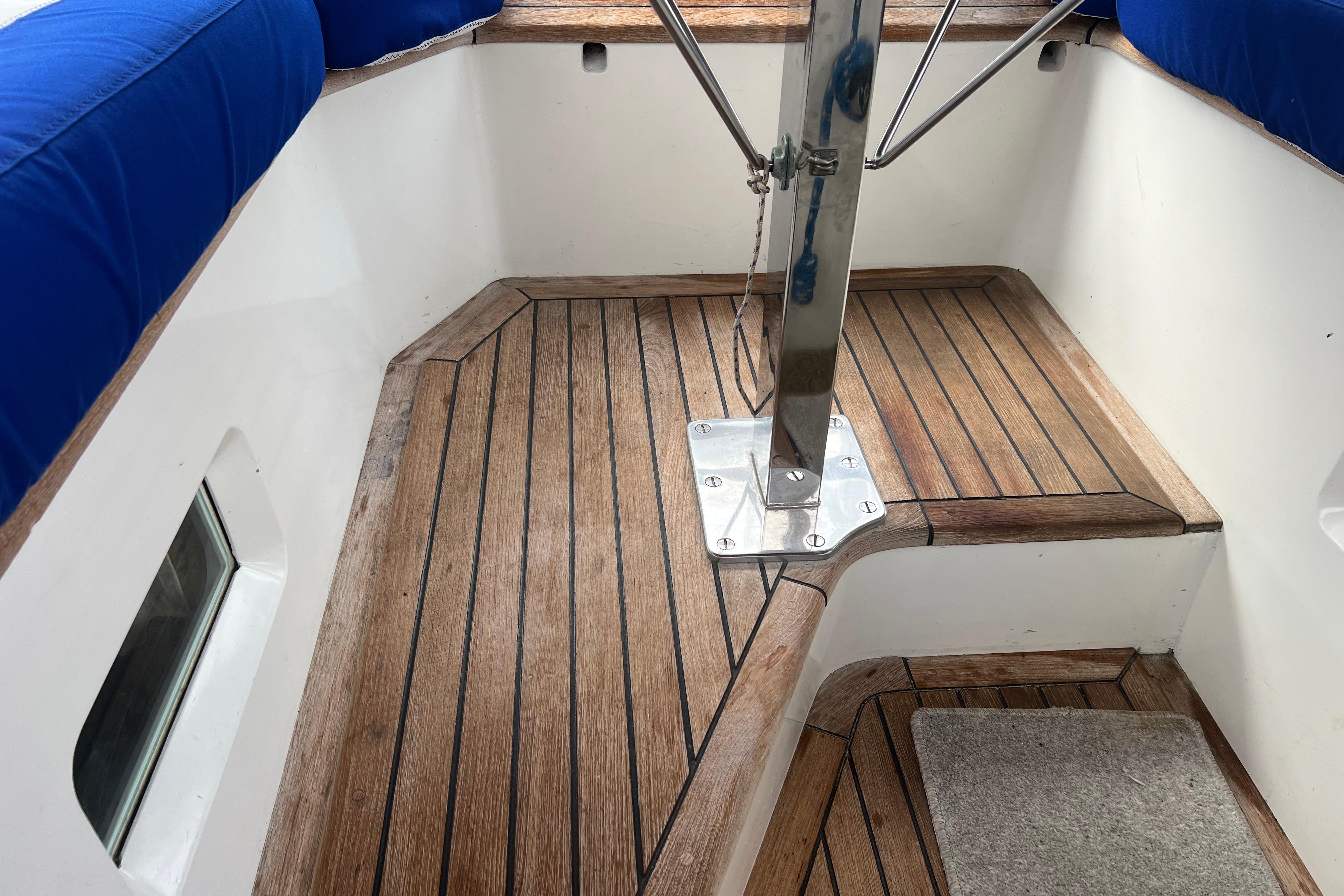 Teak deck of 1990 Trintella 49A sailboat with blue cushioned seating.