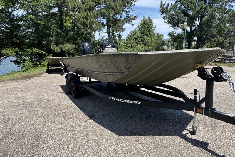 2026 Tracker Grizzly 2072 CC boat on trailer, parked outdoors near trees.