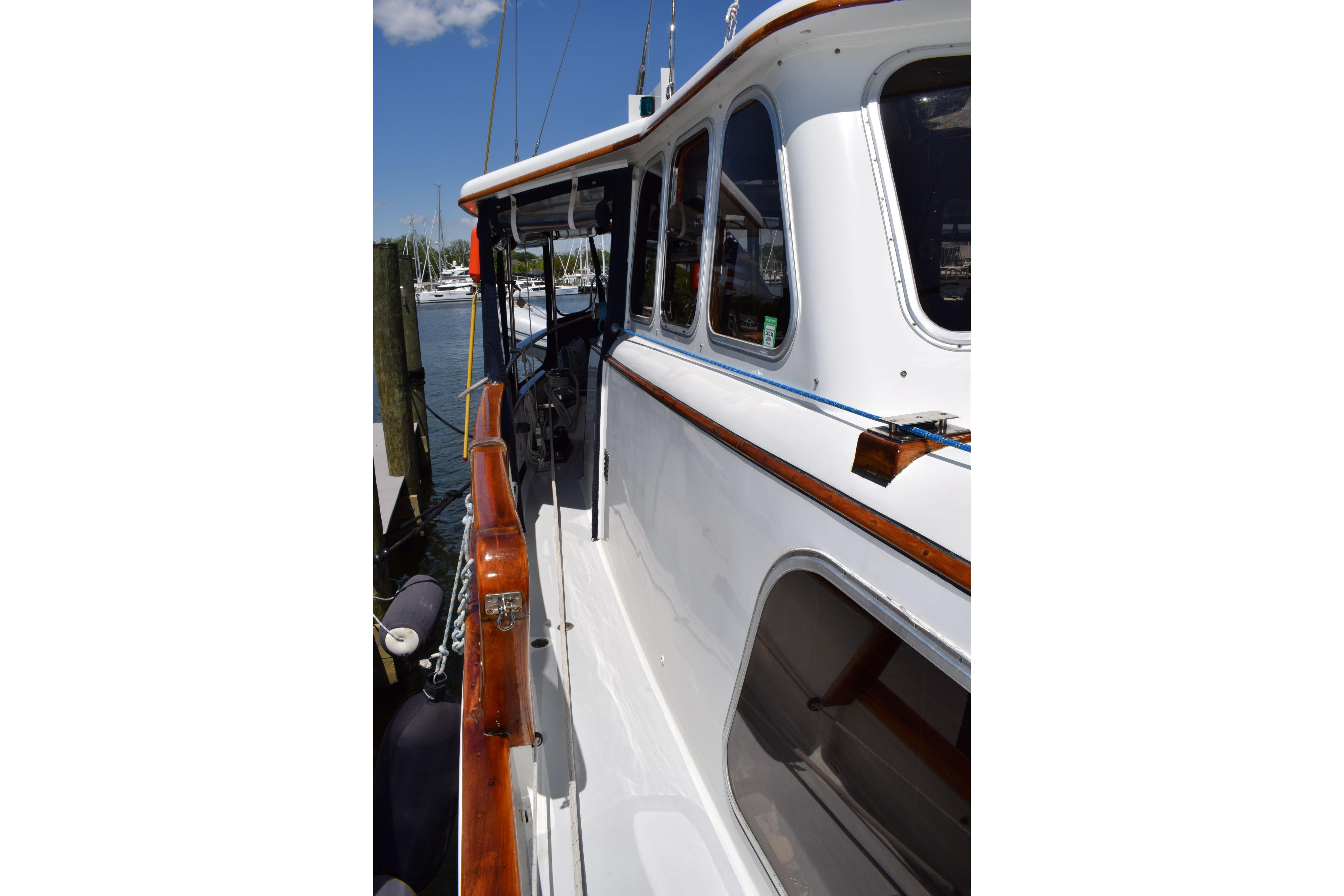 1980 Cheoy Lee 52 Motorsailer with polished wood trim docked at marina.