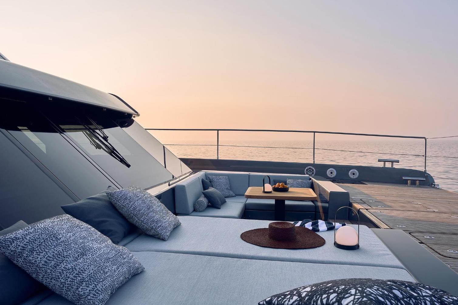 Luxurious Sunreef 60 Power yacht deck with elegant seating, cushions, and ocean view at sunset.
