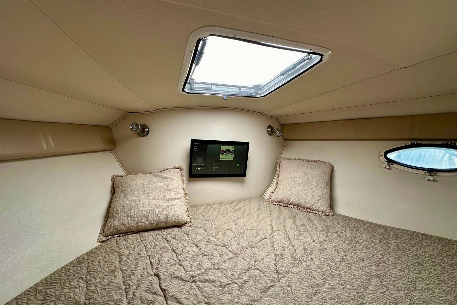 Cozy cabin interior of 2007 Larson Cabrio 330 Day Cruiser with bedding and porthole.