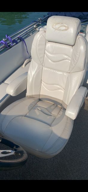 A beige captain's chair on a boat with armrests and a headrest.