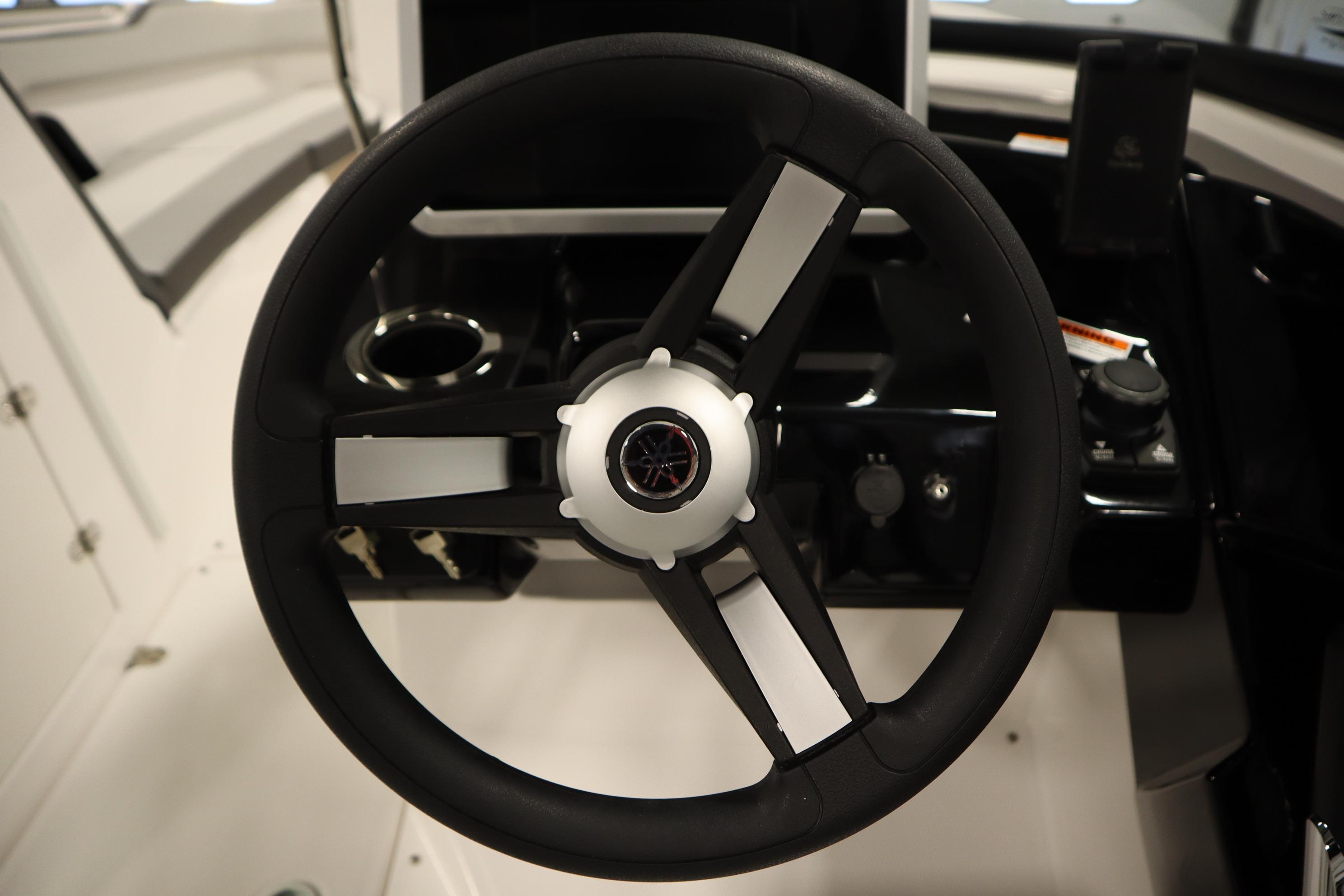 Steering wheel of 2026 Yamaha Boats AR250, featuring sleek black and white design.