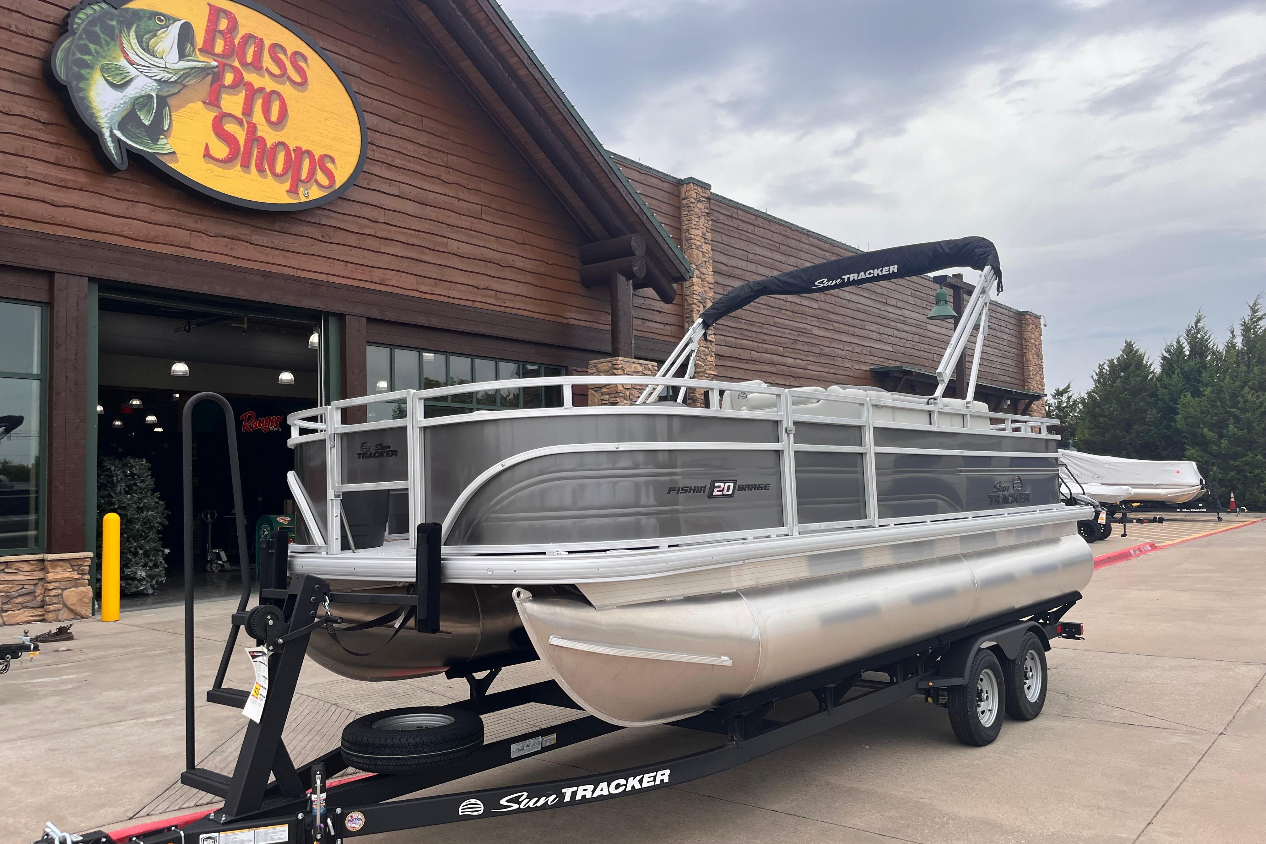 2026 Sun Tracker Fishin' Barge 20 DLX pontoon boat at Bass Pro Shops entrance.
