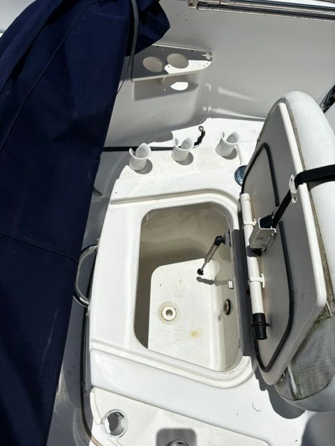 An open storage compartment on a Boston Whaler 200 Dauntless boat, surrounded by holders.