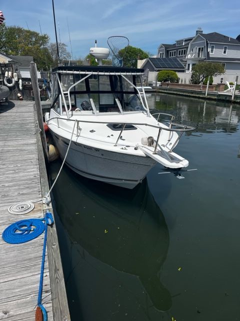 A 1998 Sport-Craft 252 Sport Fish docked. It features a white deck and black canopy.