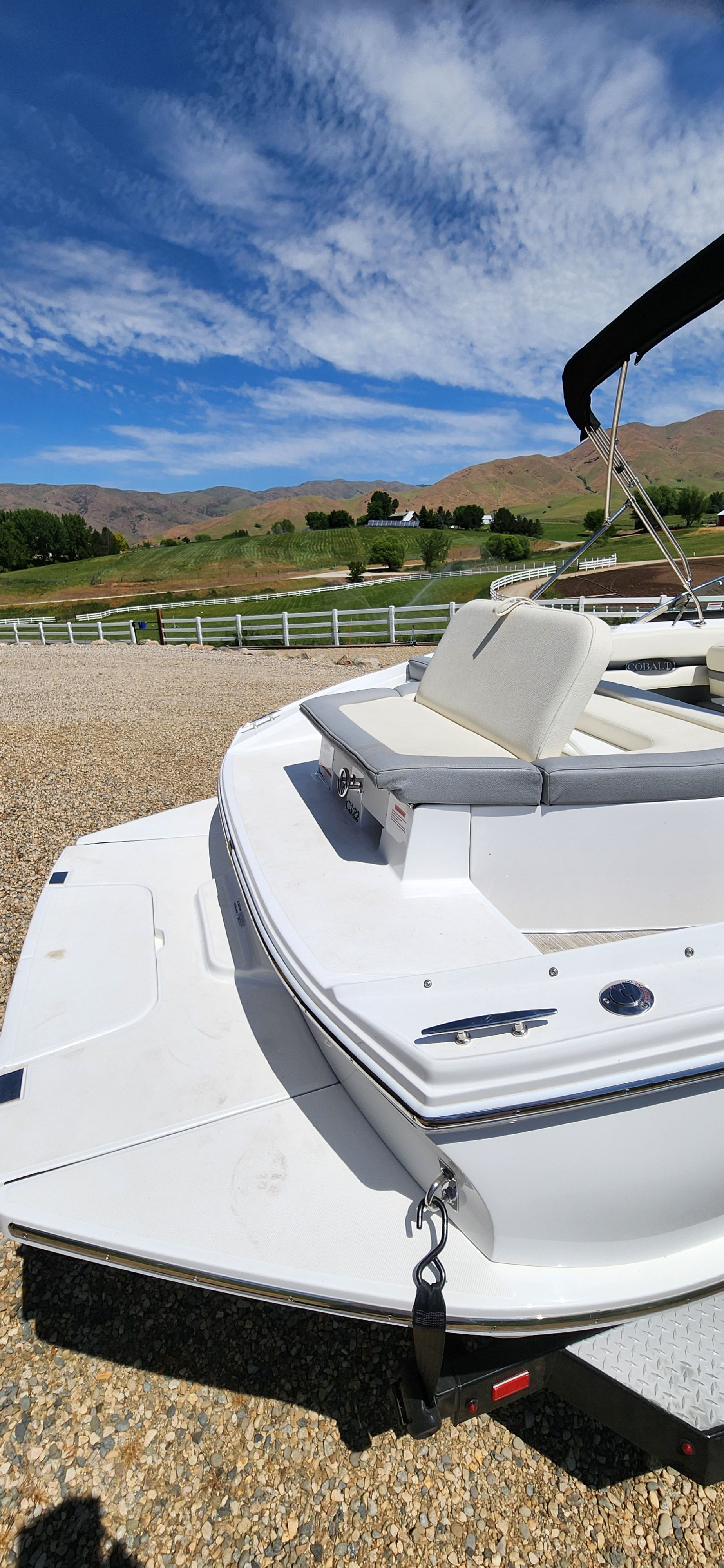 A Cobalt CS22 boat is on a trailer in a gravel lot.