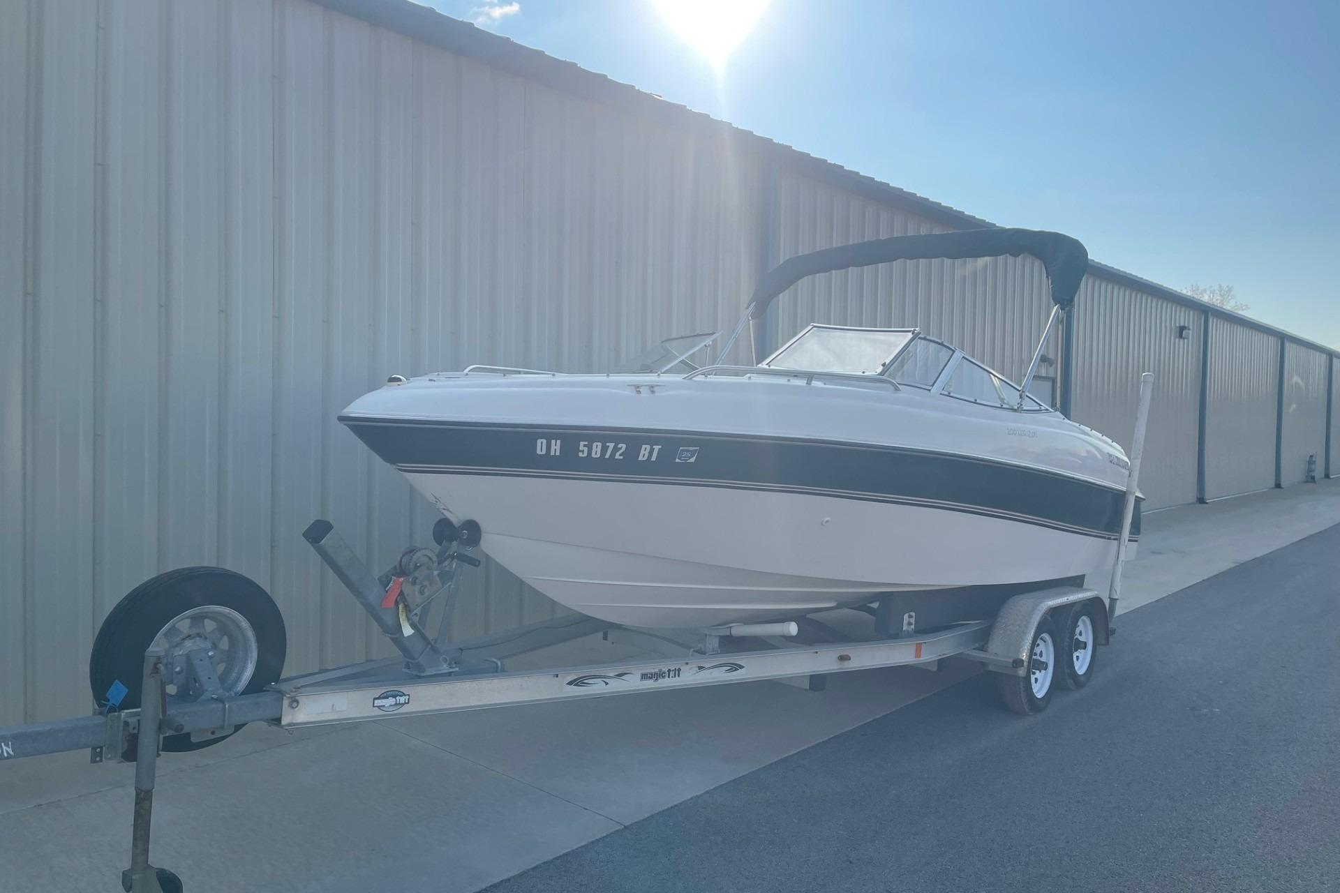 1996 Four Winns 200 Horizon boat on trailer, parked beside a large building.