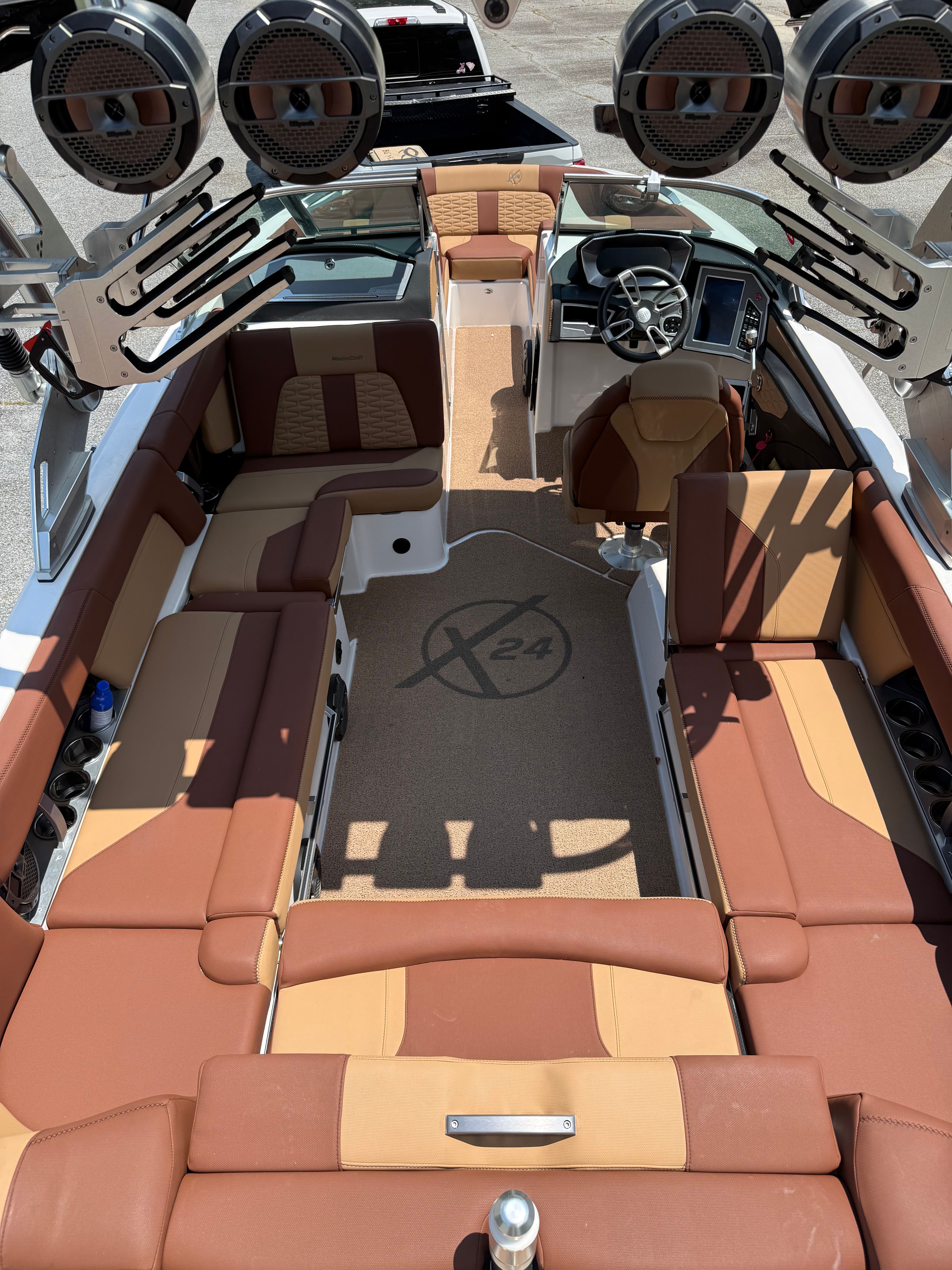 Interior view of a MasterCraft X24 boat with brown and beige seating and modern speakers.