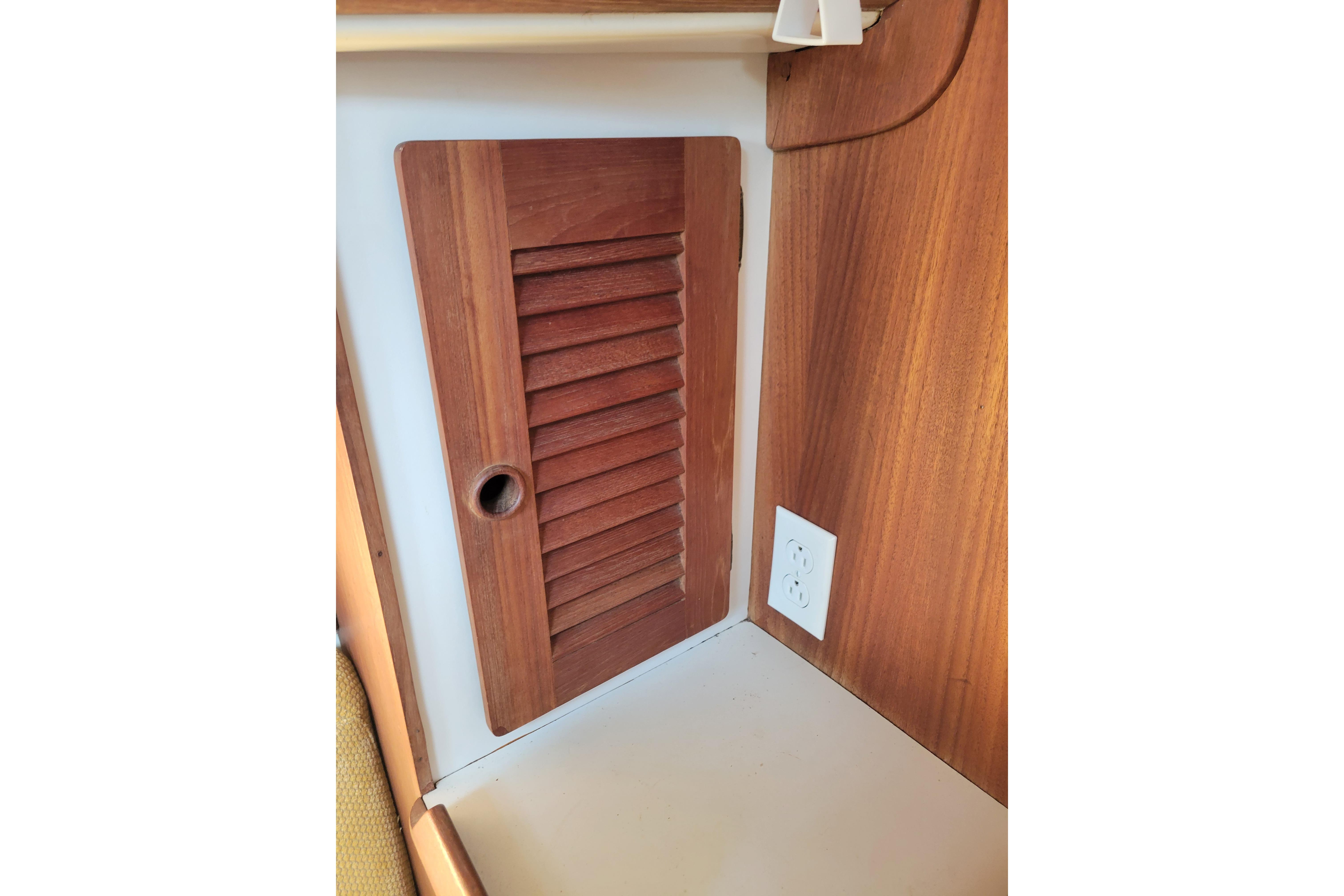 Wooden louvered cabinet door and electrical outlet in 1981 Sea Sprite 34 interior.