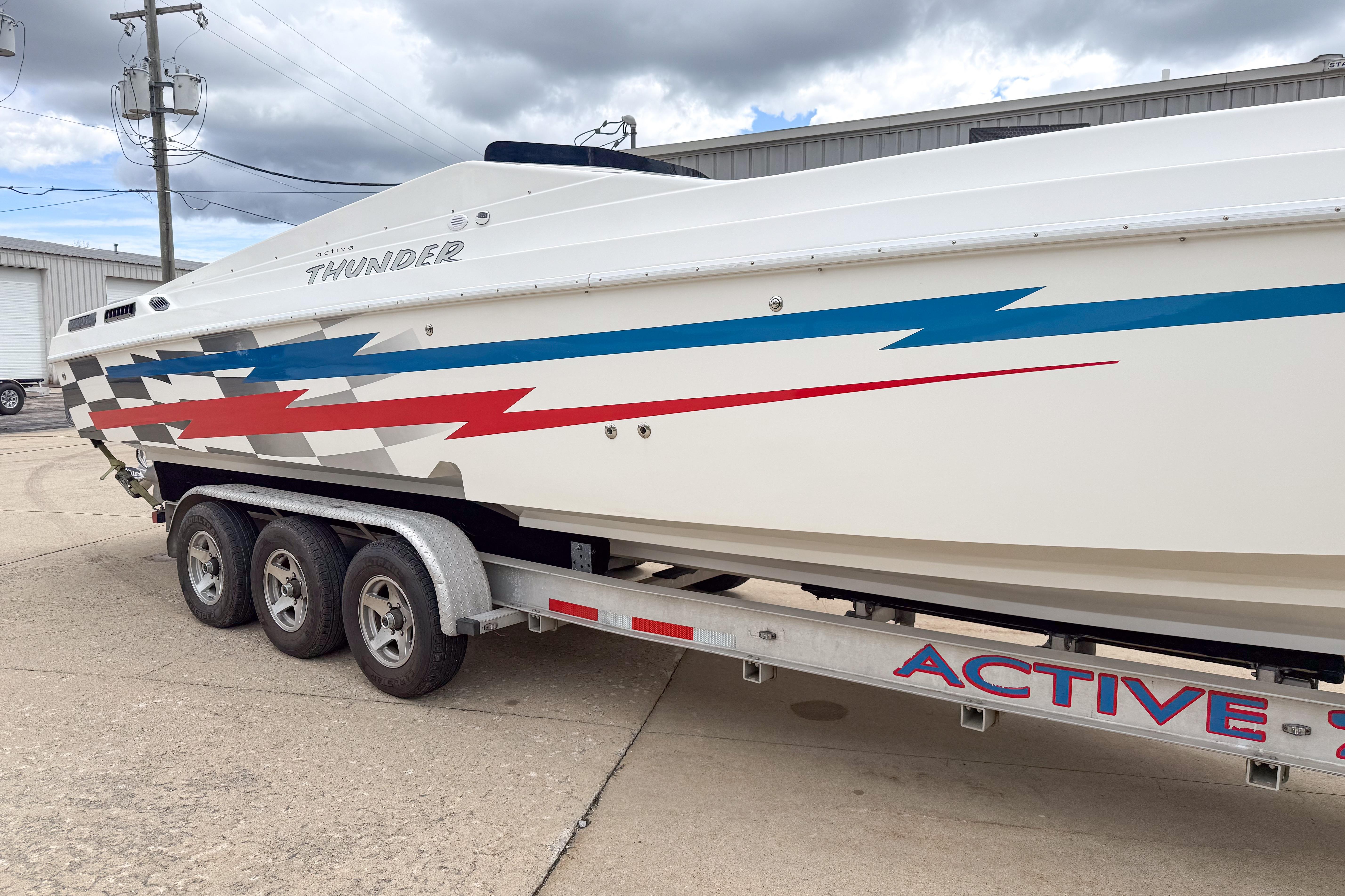 2002 Active Thunder 37 boat on trailer with colorful graphics, parked outdoors.