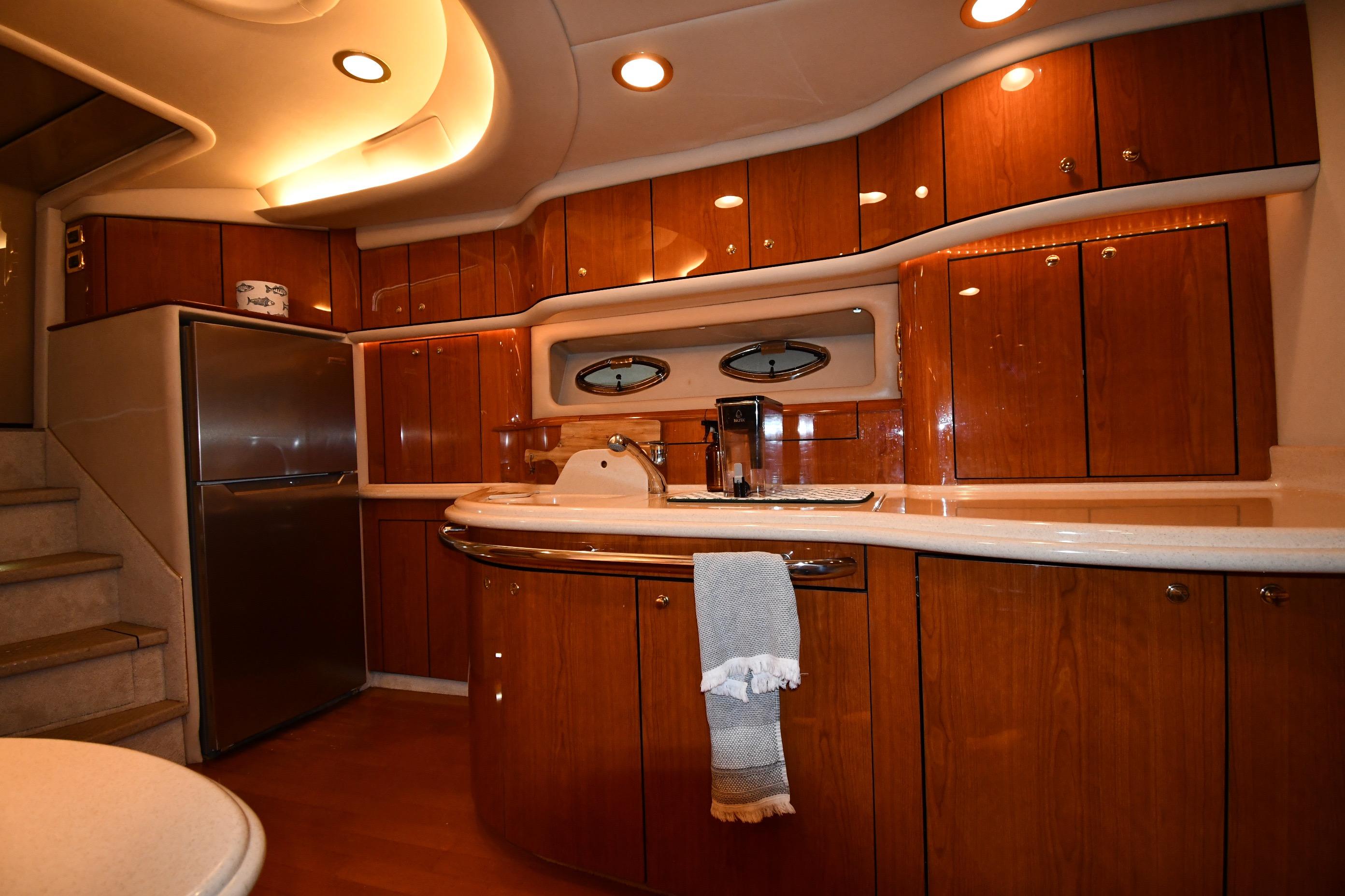 Luxurious 2001 Sea Ray 540 Sundancer yacht kitchen with wood cabinetry and modern appliances.