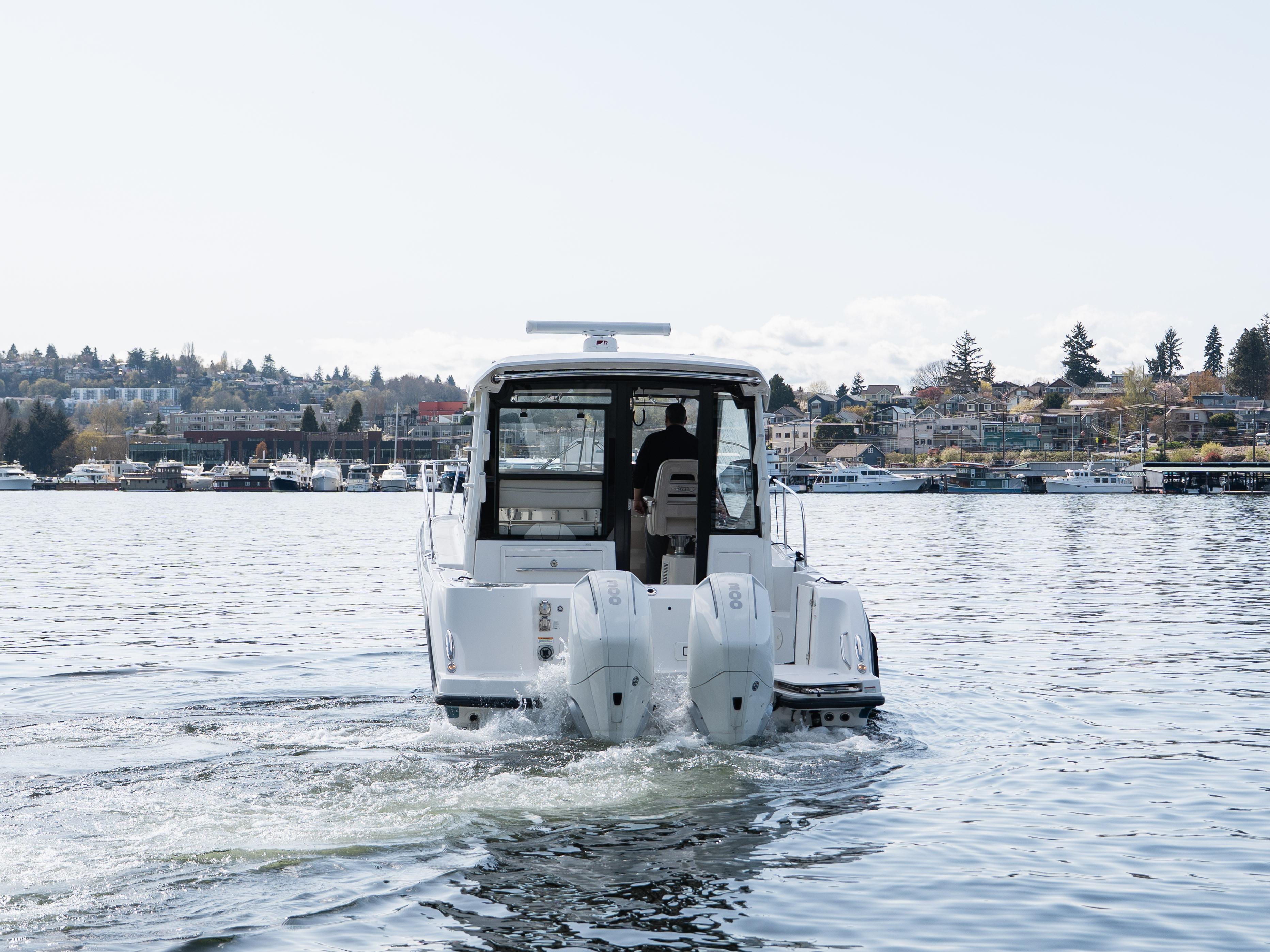 Boston Whaler 325 Conquest Pilothouse 2020 cruising on a calm lake near a town.