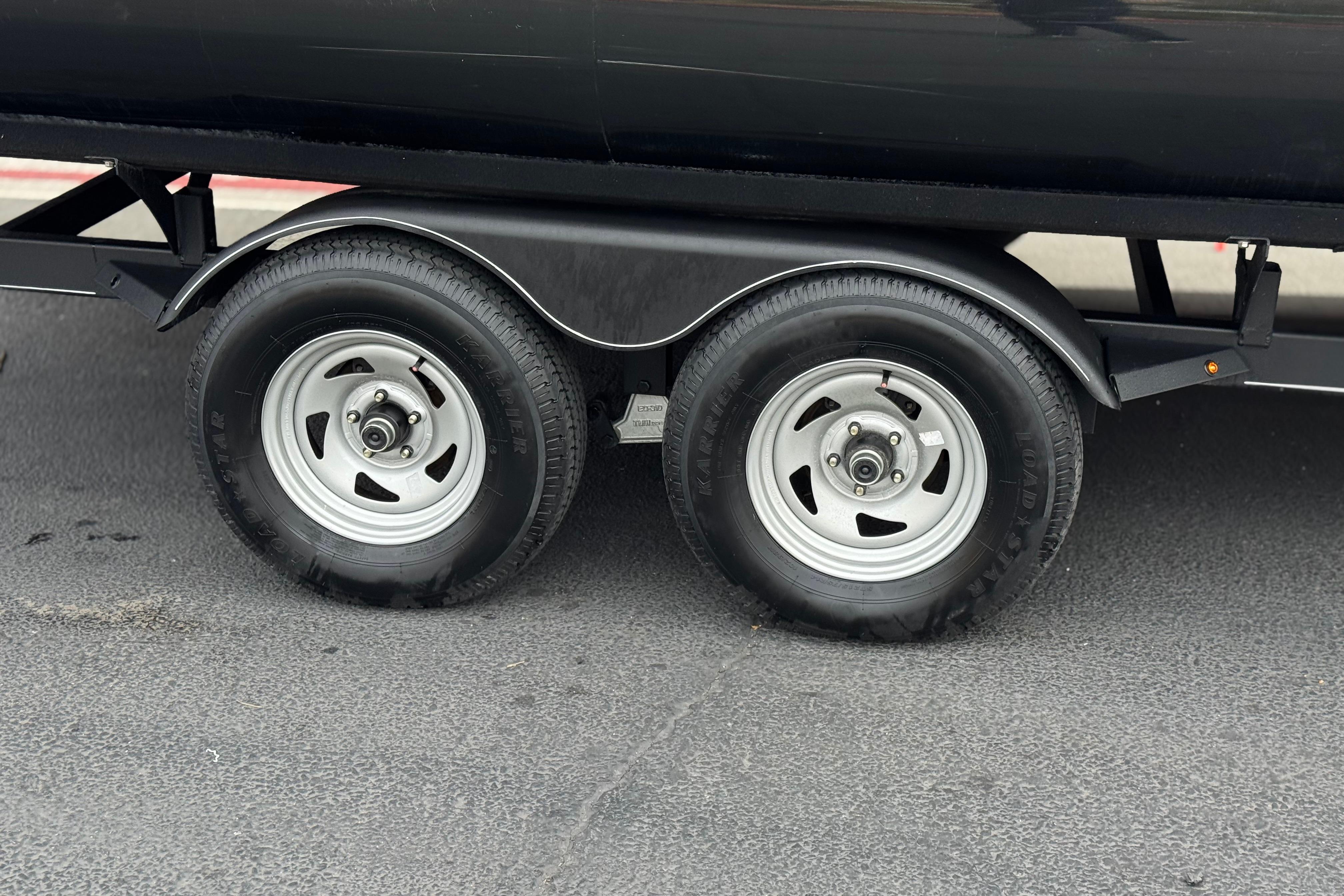 Trailer wheels of a 2022 Regency 250 DL3 boat on pavement.
