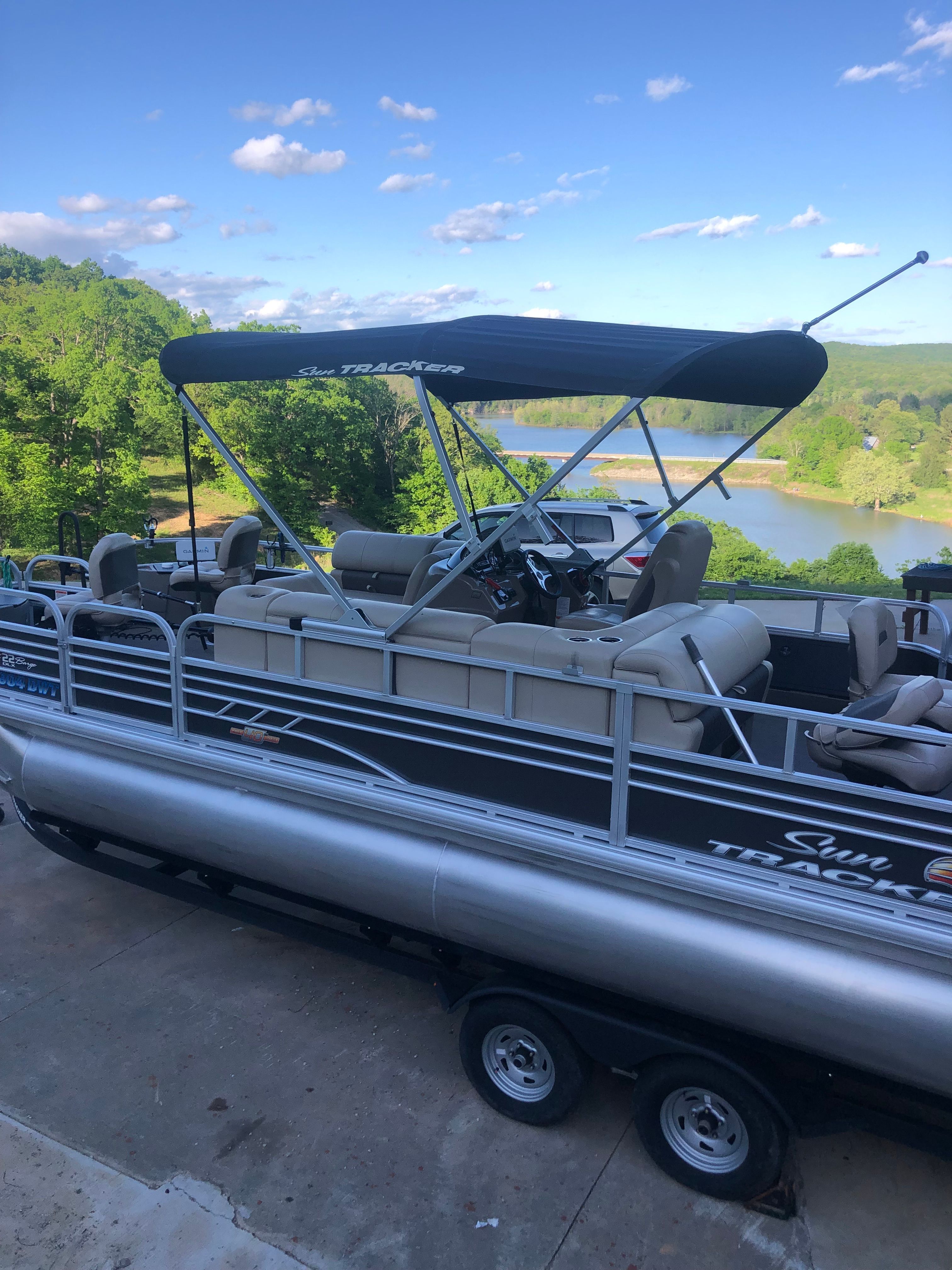 Sun Tracker Fishin' Barge 22 DLX 2023 on trailer with lake view.