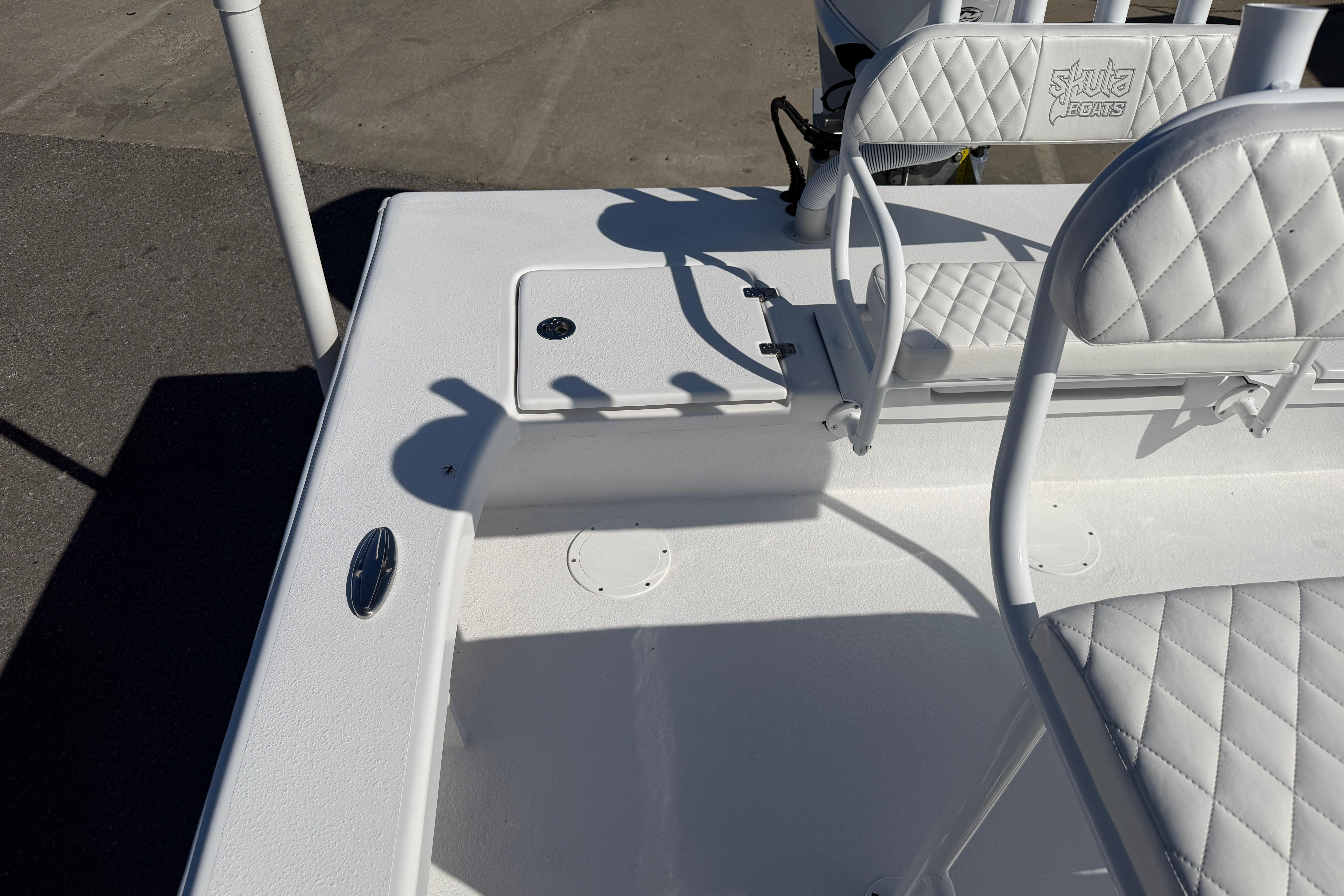 2026 Skuta 24 Cat boat interior with white quilted seating and deck details.