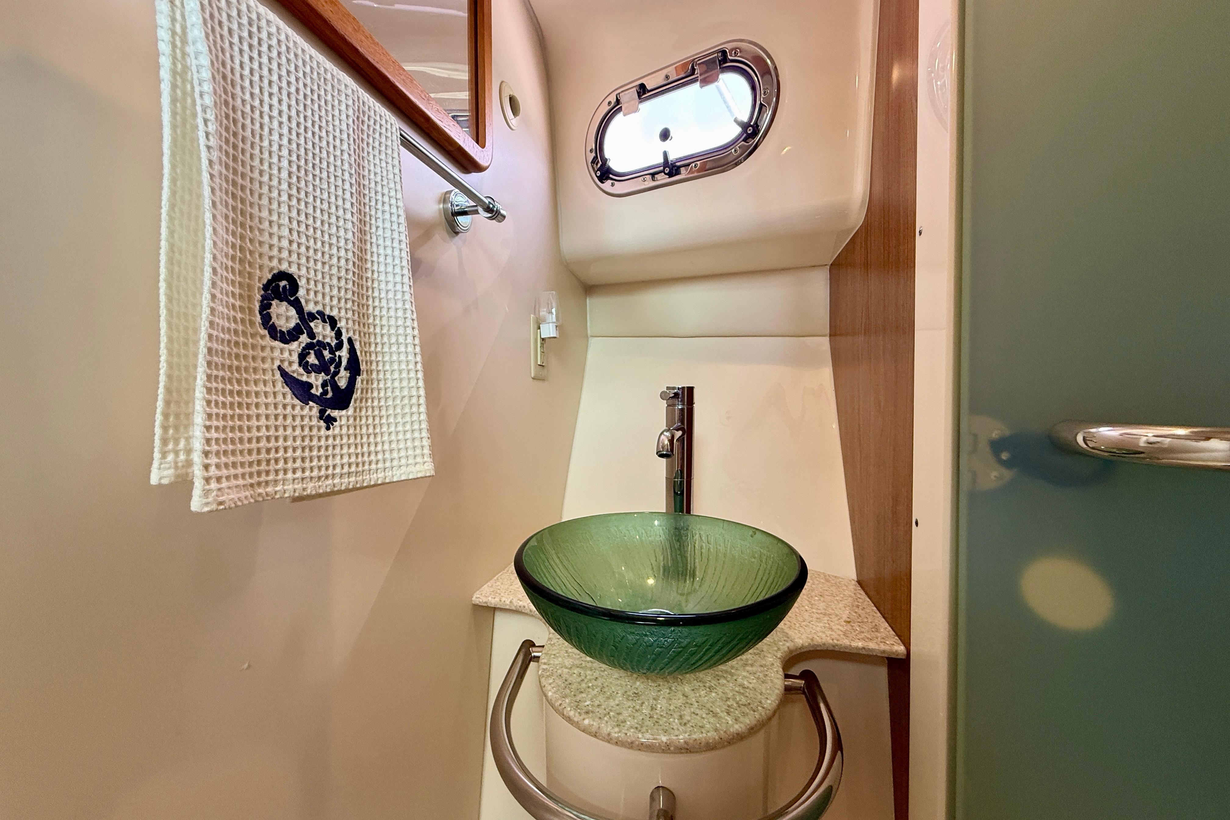 Luxurious bathroom in 2012 Pursuit OS 345 Offshore boat with glass sink and nautical decor.