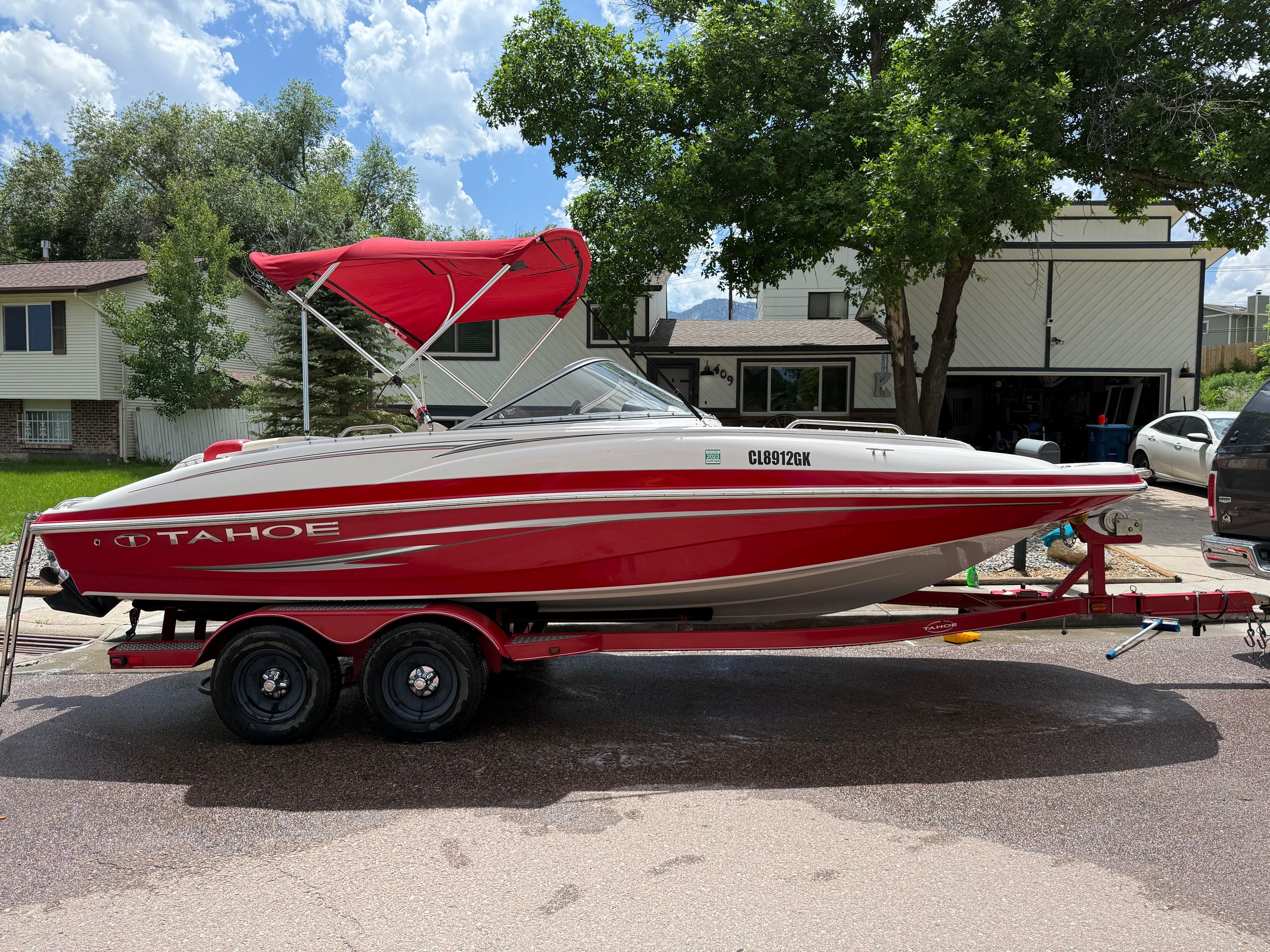 2011 Tahoe 216 WT boat on trailer, red canopy, residential area.