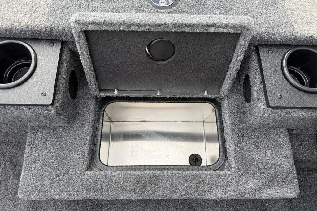 2026 Tracker Pro Team 175 boat storage compartment with cup holders, open lid, and carpeted interior.
